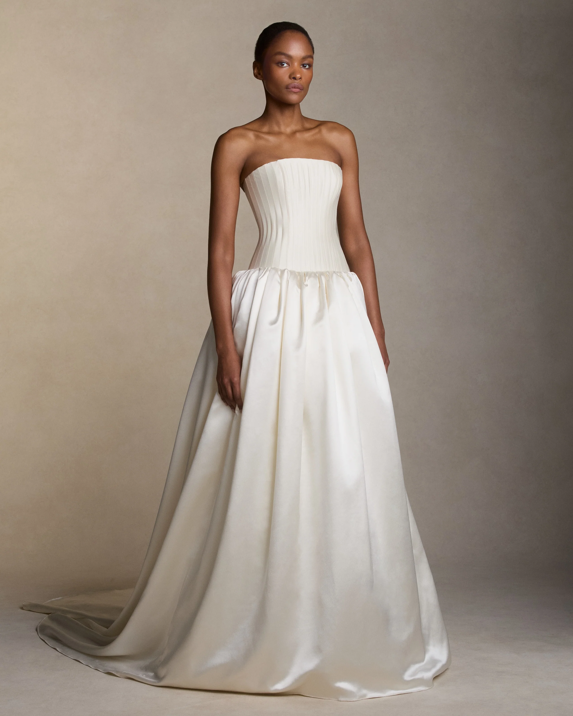Silk wool strapless drop waist ballgown with trapunto-stitched boning shaping the bustier. Silk wool twill bodice releases into a silk wool satin gathered ball skirt. Boned internal bustier, internal grosgrain belt and invisible zip closure at center back.