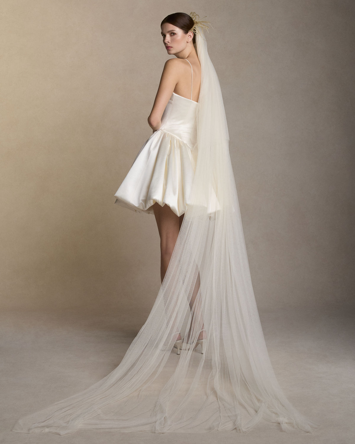 Soft tulle veil with feather detail framing the crown of the head. 104