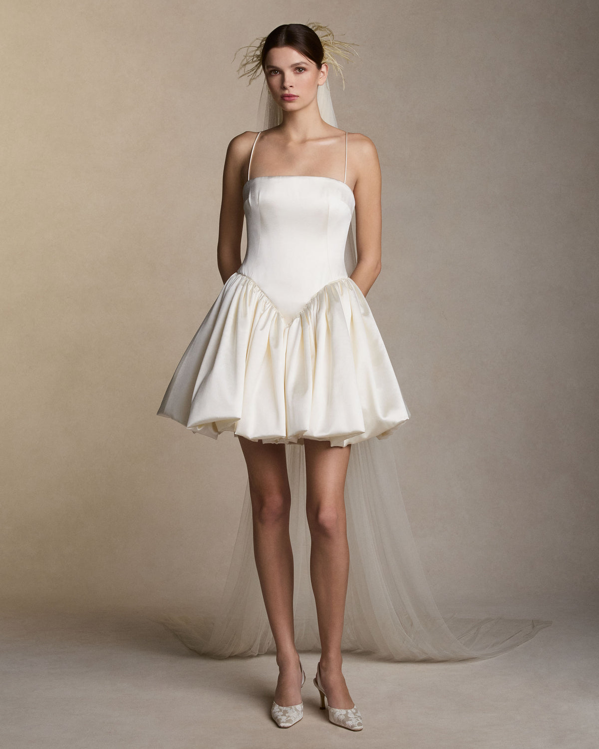 Soft tulle veil with feather detail framing the crown of the head. 104