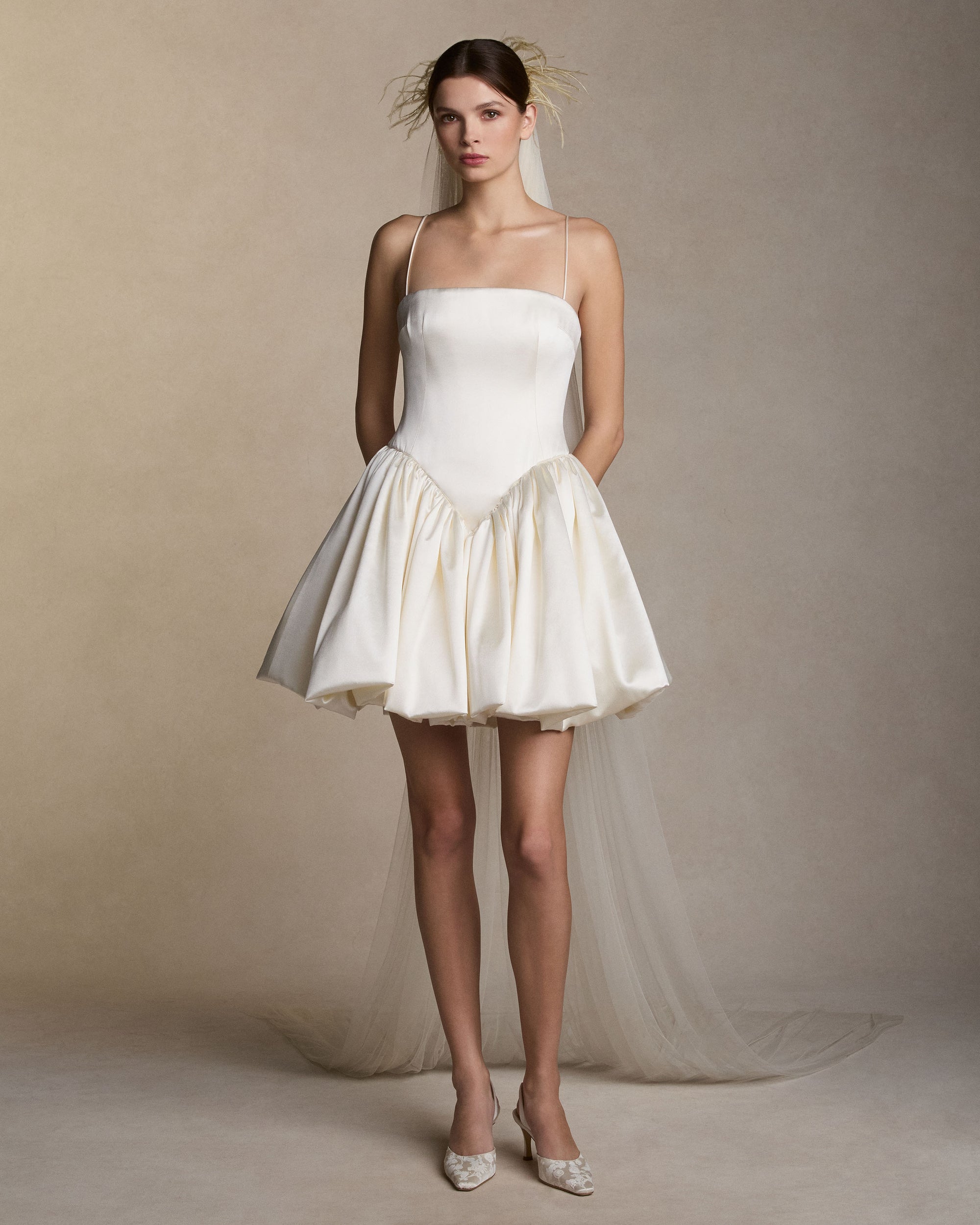 Soft tulle veil with feather detail framing the crown of the head. 104" from comb to hem.