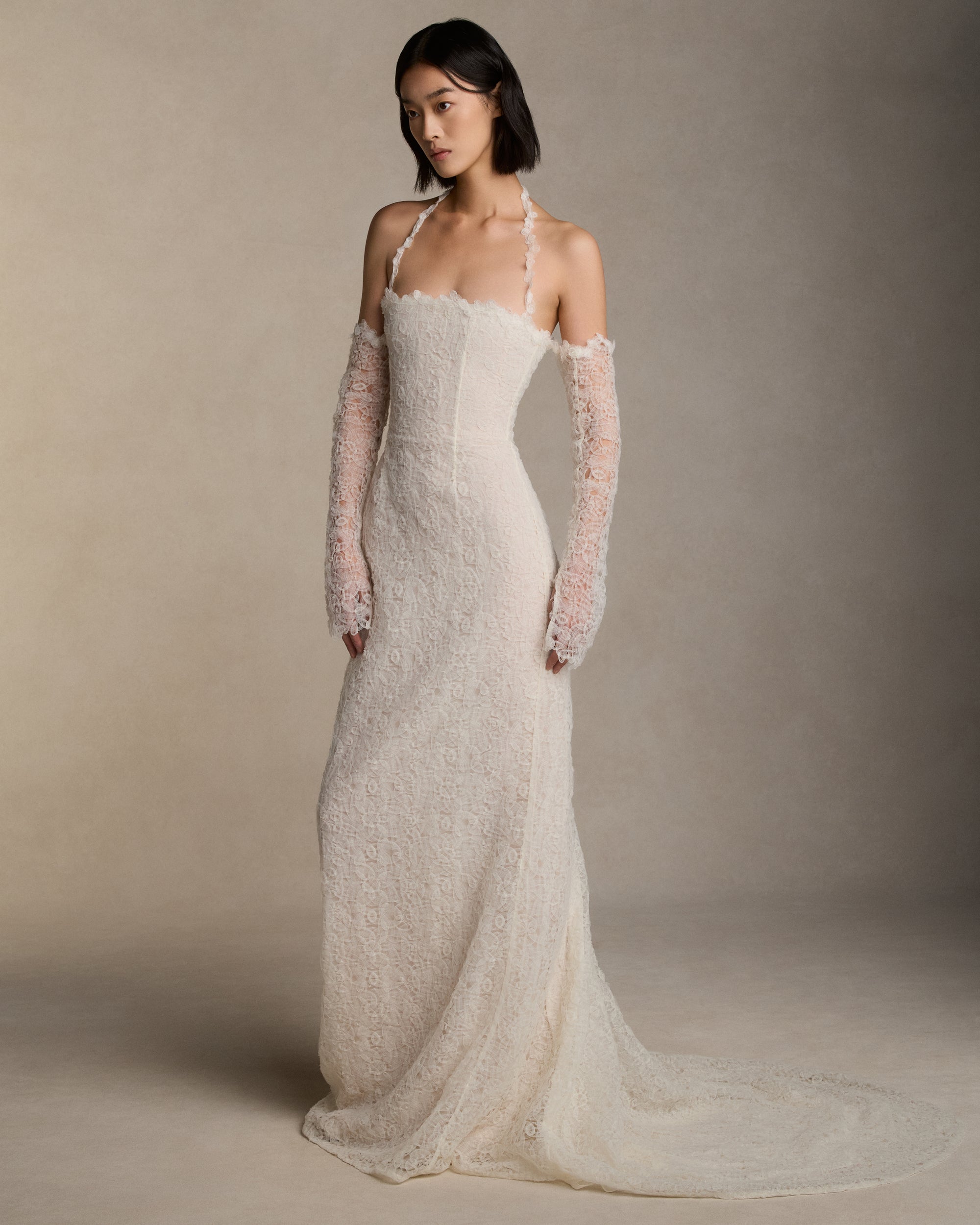 Delicate tulle labyrinth embroidered halter gown with crinkle organza looped trim decorating the neckline. Removable tulle labyrinth embroidered sleeves adorn the arms. Invisible zip closure at center back.