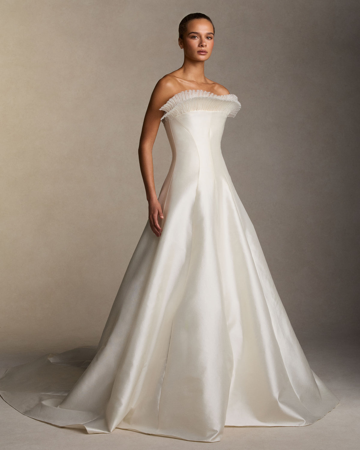 Silk wool twill strapless ball gown with layered crinkle and satin organza fan embroidery radiating from the neckline. Shaped seams define the waist, releasing into a full ball skirt. Boned internal double zip bustier with internal grosgrain belt. 