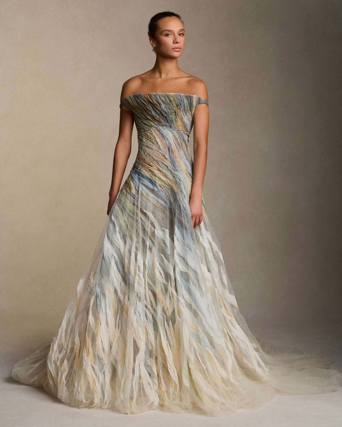 Strapless illusion tulle gown with sculptural flared neckline. Hand dyed hand cut silk chiffon watercolor strips ripple around the body, cascading into a bubble hem. Boned internal bustier, internal grosgrain belt and invisible zip closure at center back.