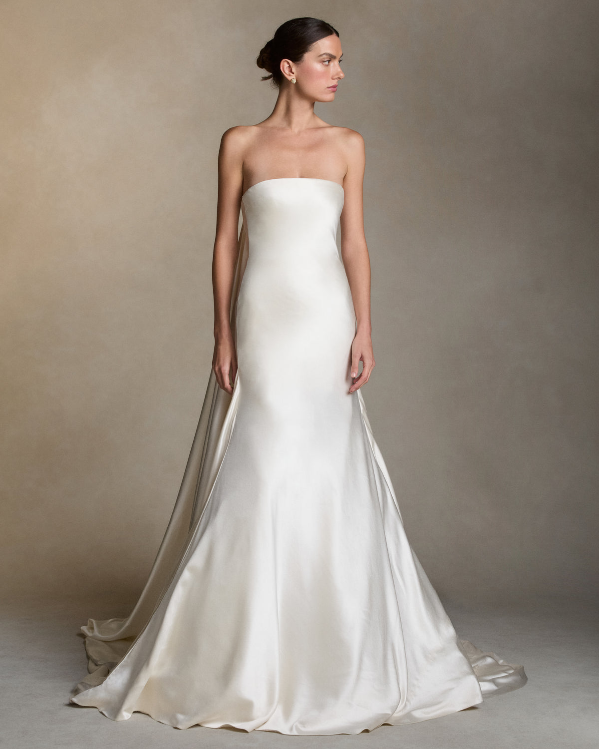 Silk wool column gown with a dramatic gathered ball skirt. Fluid draping cascades from the side seam into a center back watteau, extending into a sweeping train.