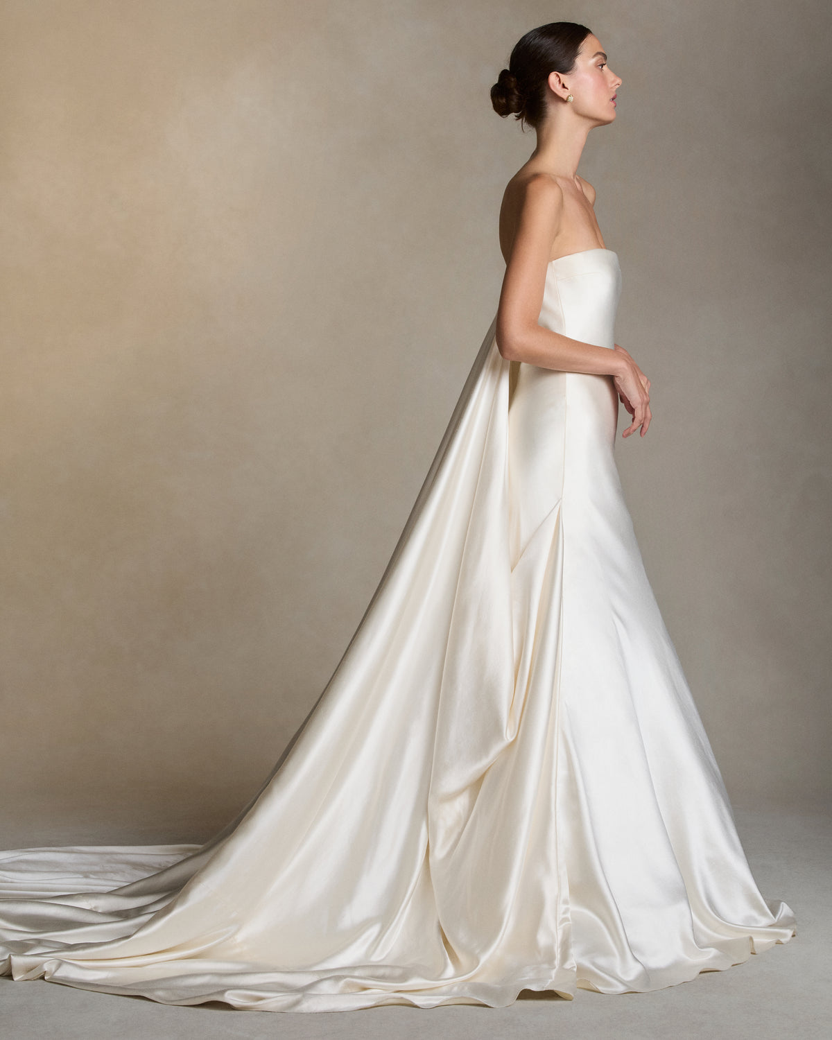 Silk wool column gown with a dramatic gathered ball skirt. Fluid draping cascades from the side seam into a center back watteau, extending into a sweeping train.