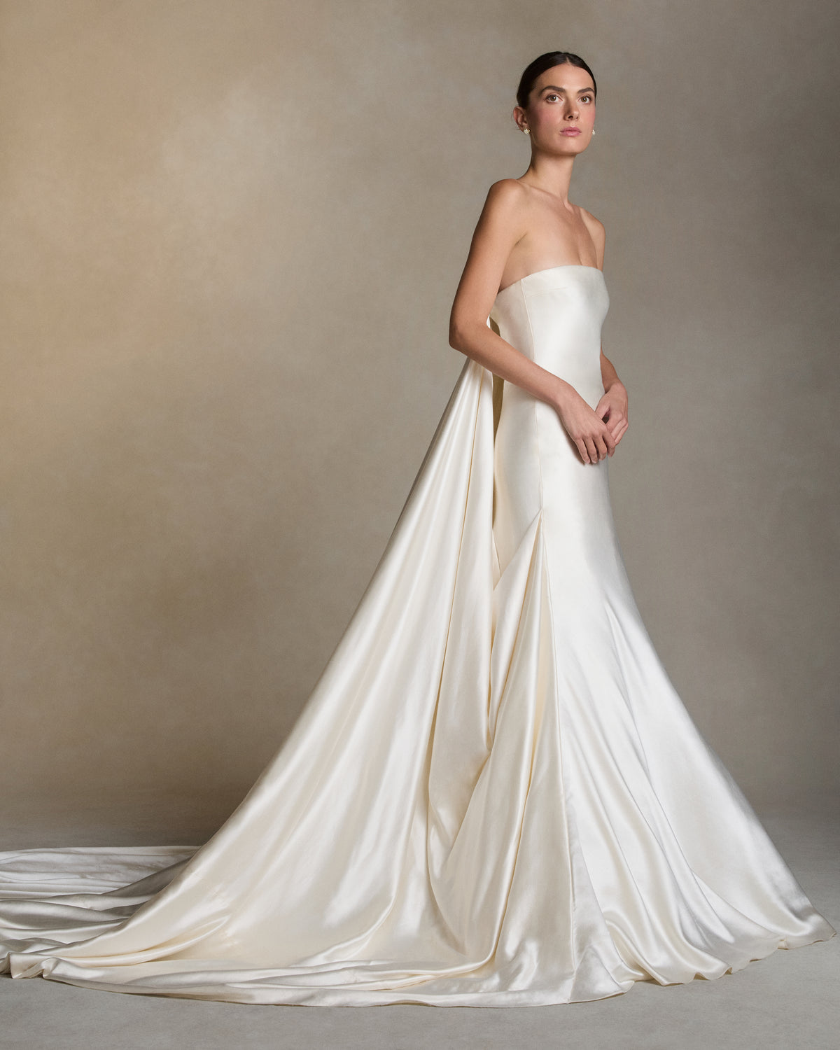 Silk wool column gown with a dramatic gathered ball skirt. Fluid draping cascades from the side seam into a center back watteau, extending into a sweeping train.