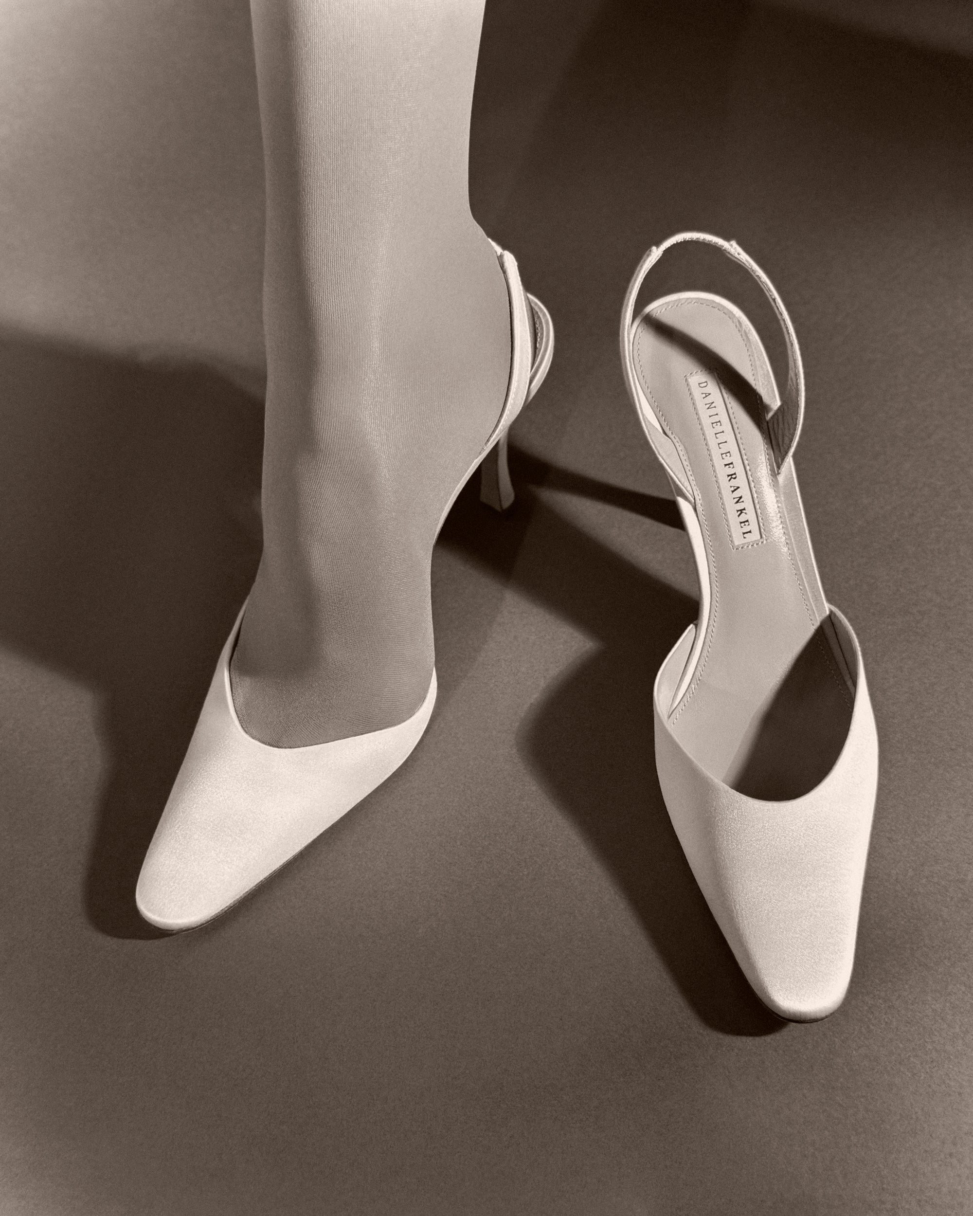 Classic slingback crafted in Italy of ivory satin. Elongated round toe and 90mm heel.