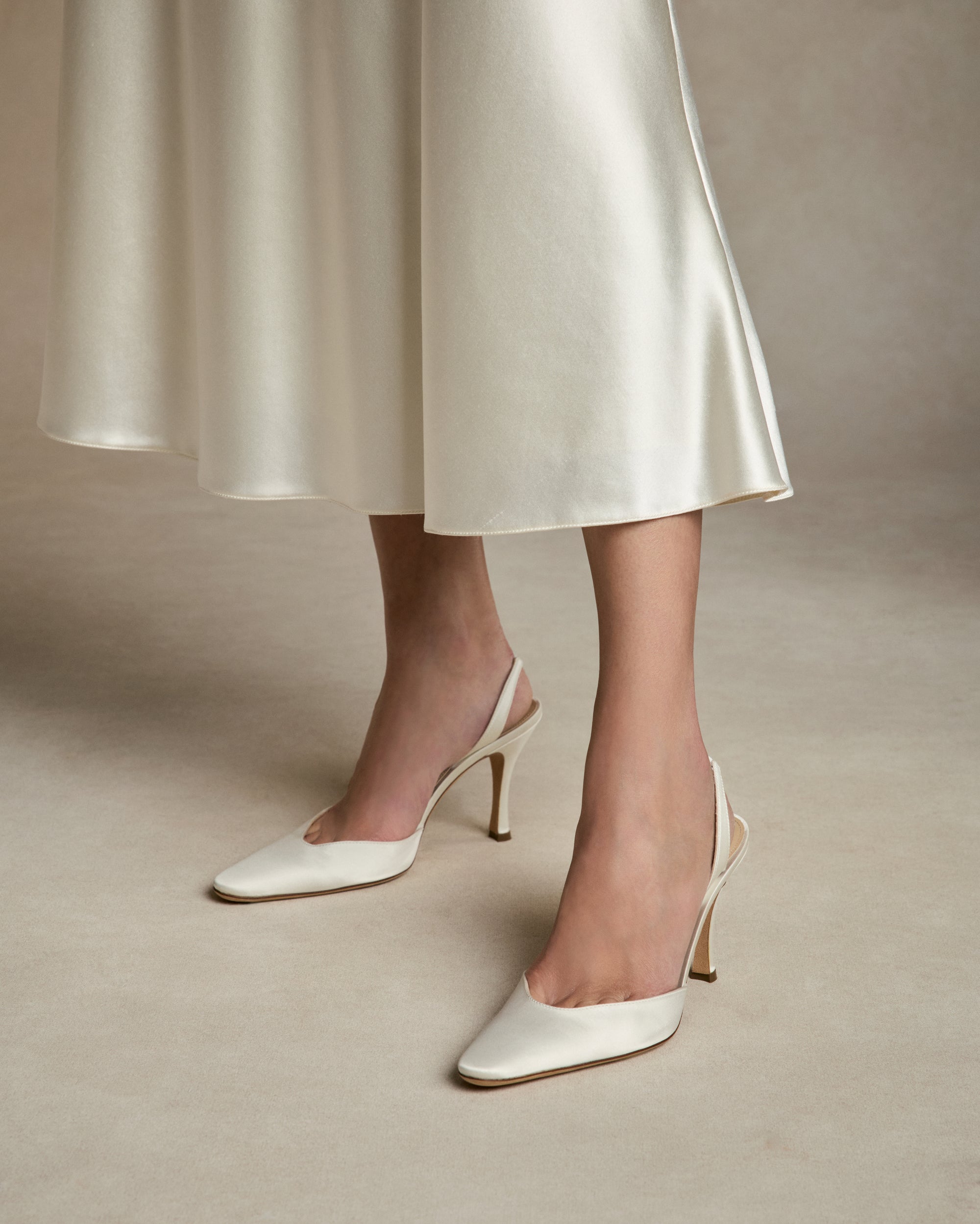 Classic slingback crafted in Italy of ivory satin. Elongated round toe and 90mm heel.