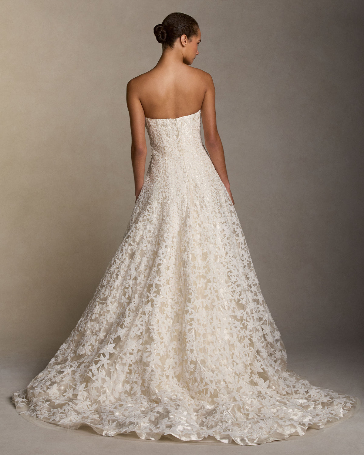 Strapless ball gown with star flower pearl embroidery layered over pewter metal and silk satin. Thousands of hand cut silk chiffon petals with baroque pearls veil a layer of lustrous crinkled metal and silk. Interior lace-up corset with a grosgrain waist belt and double-zip bustier for added structure.