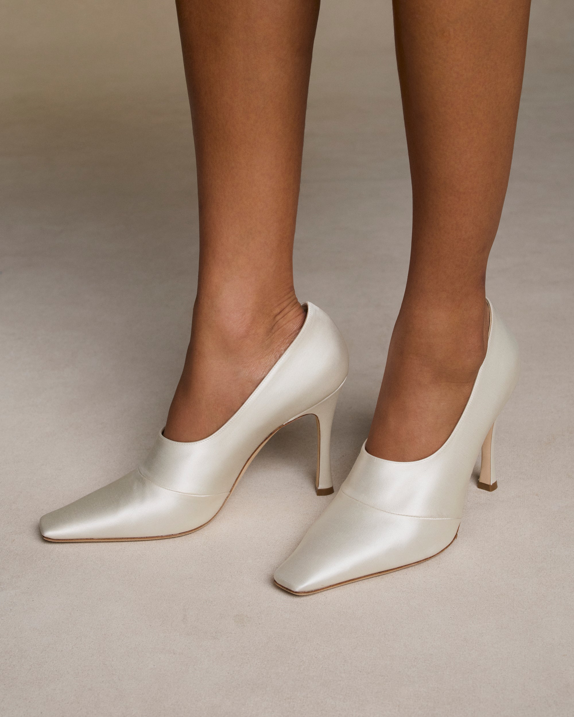 Ivory satin square toe high vamp pump with shaped seam detail.  100mm heel. Hand crafted in Italy. 