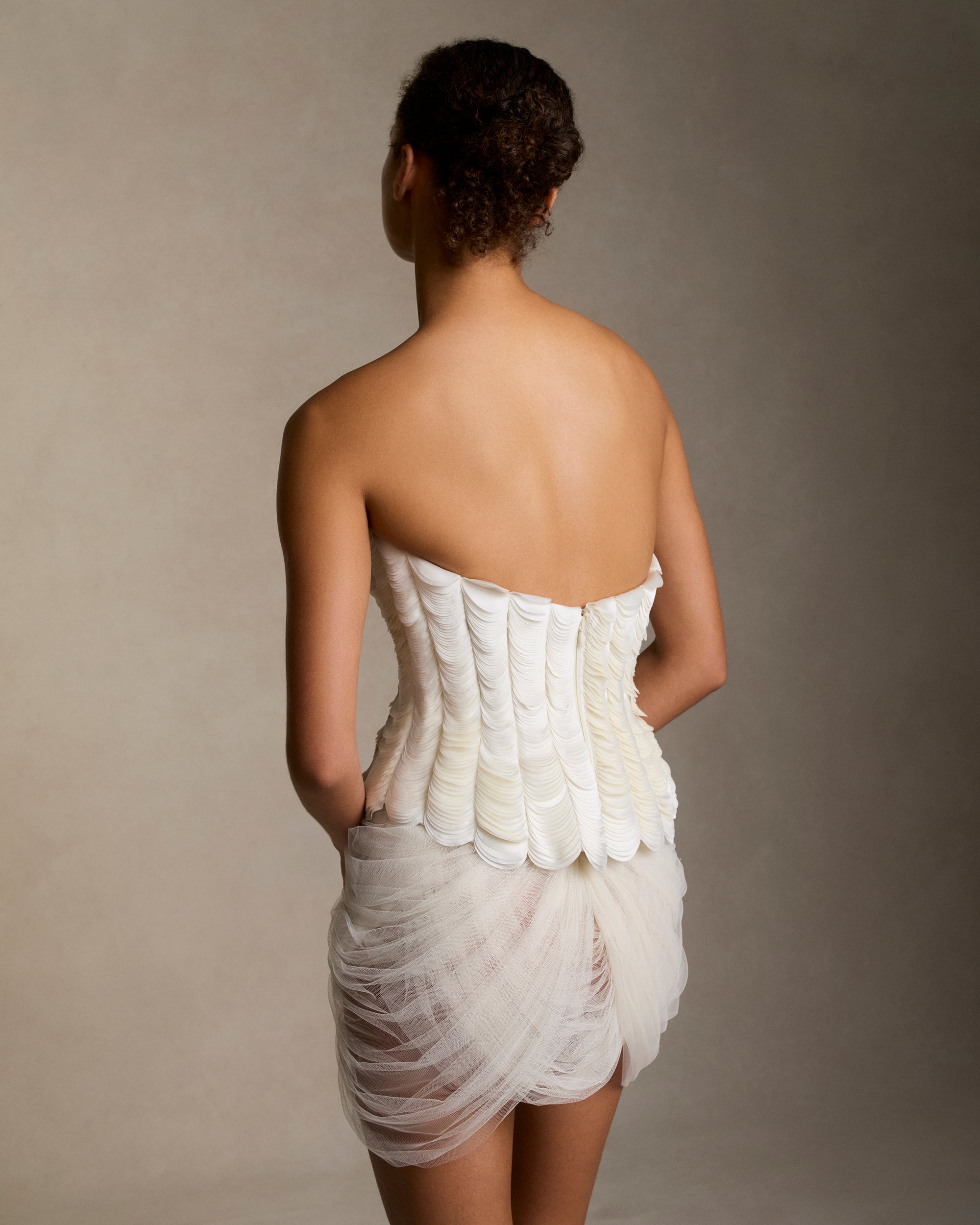 Structured bustier with thousands of layered satin petals shaping the flared neckline silhouette. Boned internal bustier, internal grosgrain belt and invisible zip closure at center back.Styled with Dree skirt &amp; Tess skirt