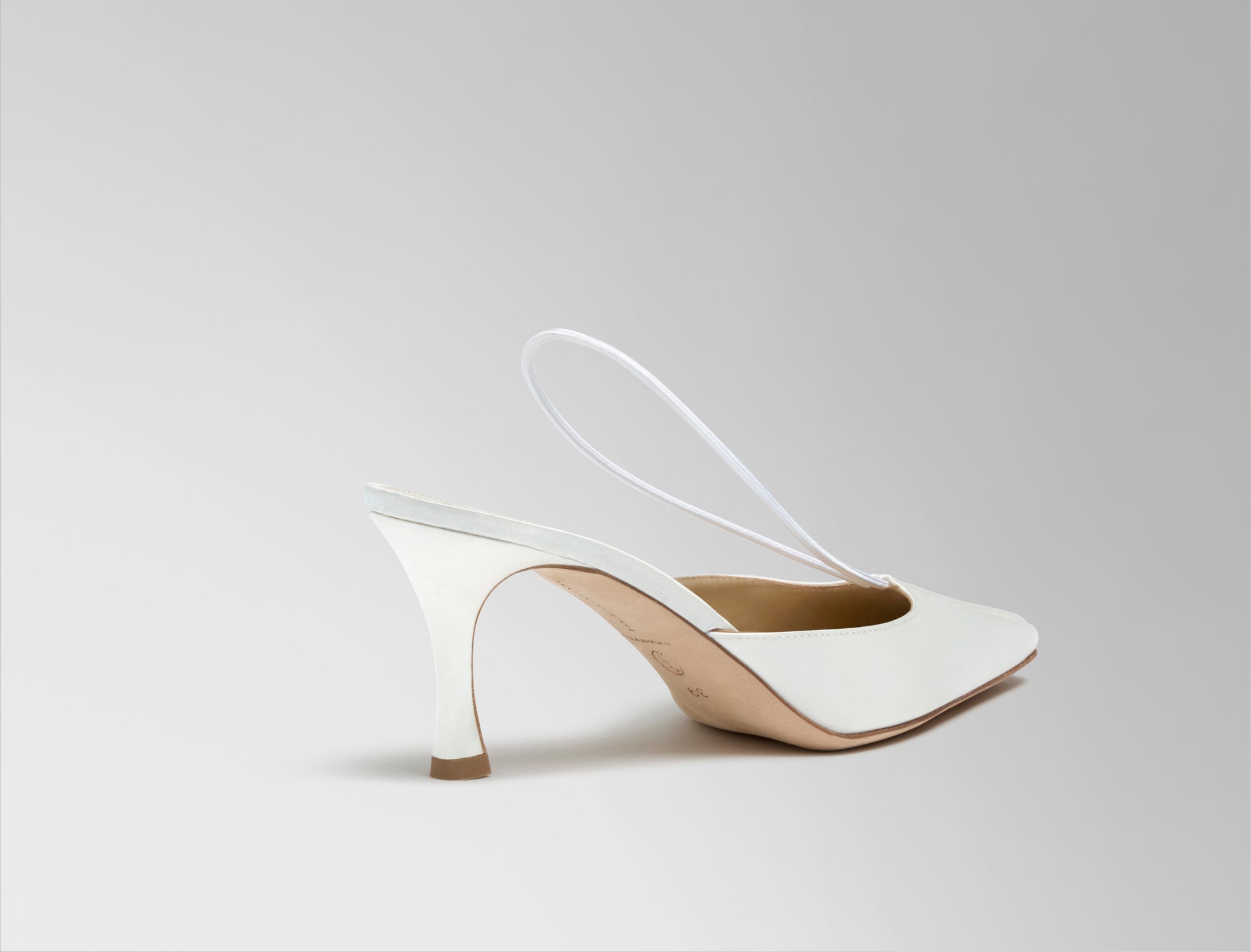 70mm rounded square toe mule crafted in Italy of ivory satin. Elastic sling back wraps around the foot, finishing into a channel detail at toe.