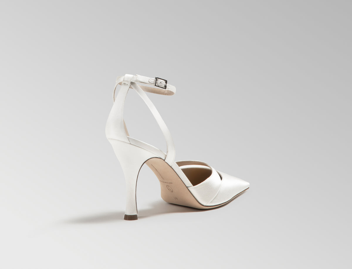Ivory satin square toe pump with cutout detail at toes. Straps loop around ankle finishing in a buckle closure. 100mm heel. Hand crafted in Italy.