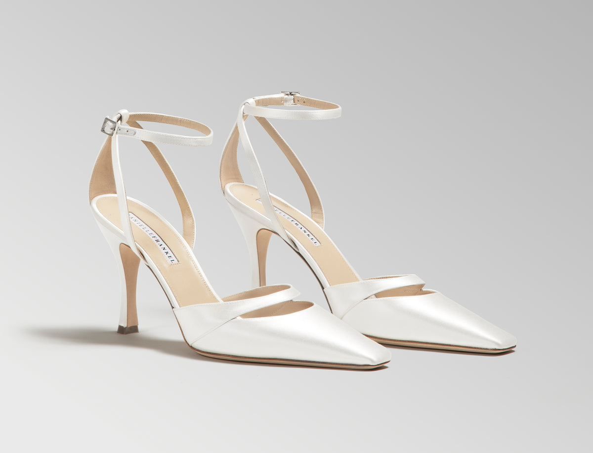 Ivory satin square toe pump with cutout detail at toes. Straps loop around ankle finishing in a buckle closure. 100mm heel. Hand crafted in Italy.