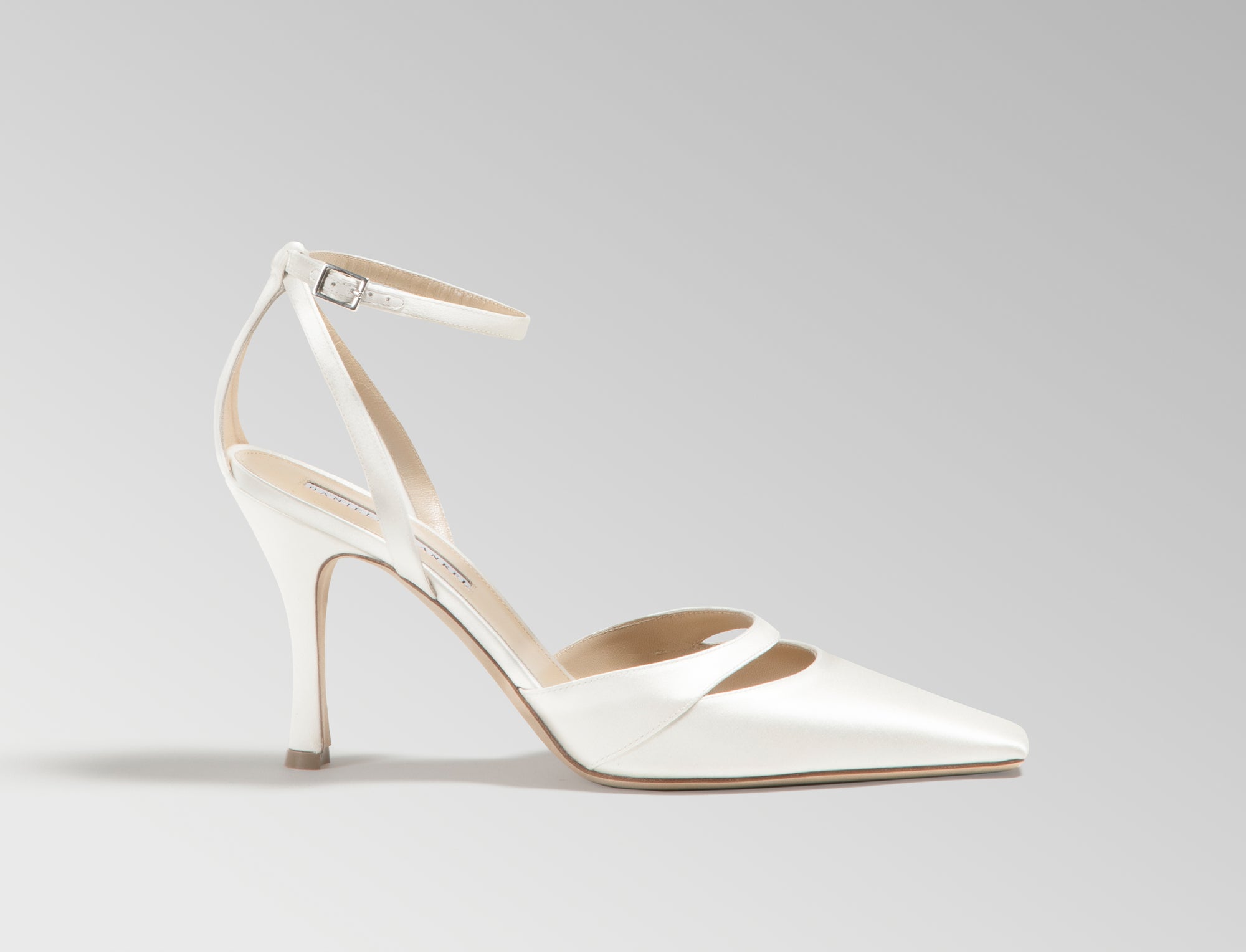 Ivory satin square toe pump with cutout detail at toes. Straps loop around ankle finishing in a buckle closure. 100mm heel. Hand crafted in Italy.