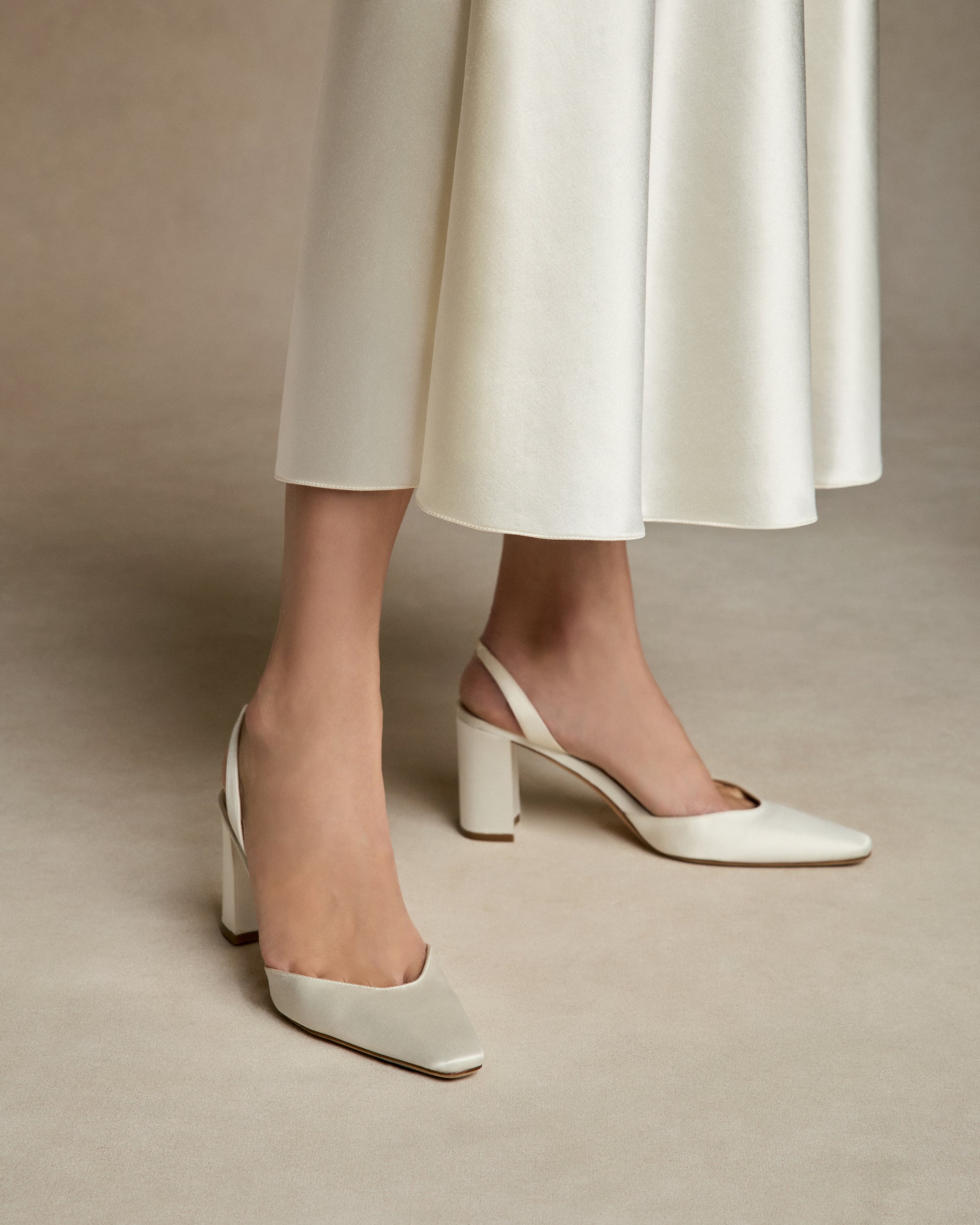 Classic rounded square toe slingback crafted in Italy of ivory satin. 75mm block heel.
