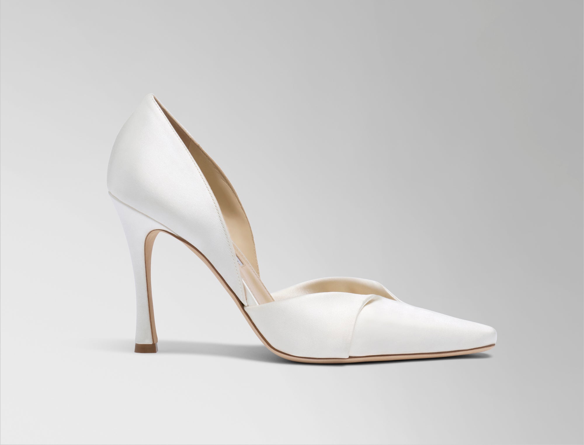 Rounded square toe pump crafted in Italy of ivory satin. Sculpted satin detail peels away at neckline as it wraps around the foot. 100mm heel.