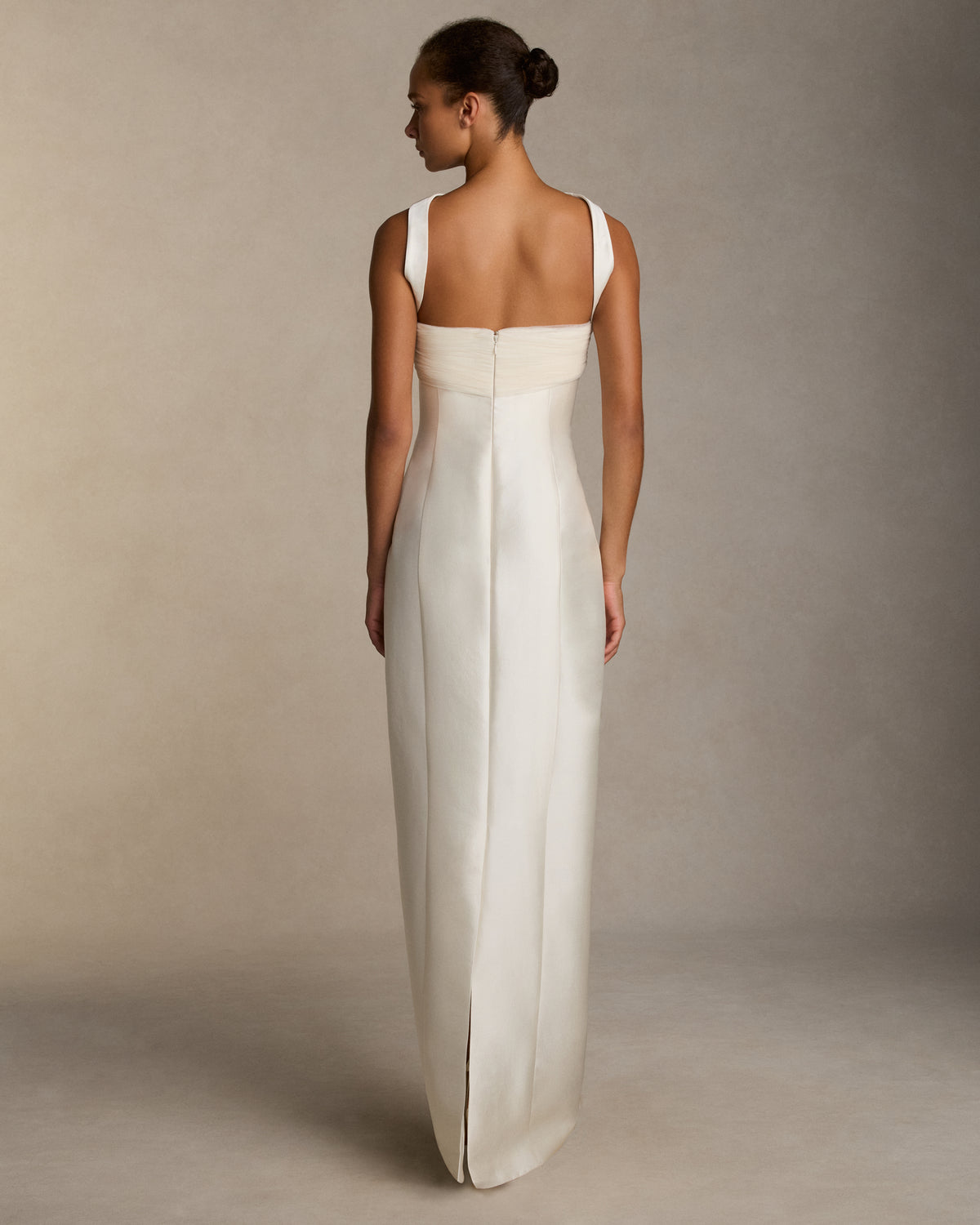 Silk wool twill column gown with curved shaped seams and attached neck wrap detail. Gathered and draped tulle frames the bust wrapping towards the center back. Boned internal bustier, internal grosgrain belt and invisible zip closure at center back.