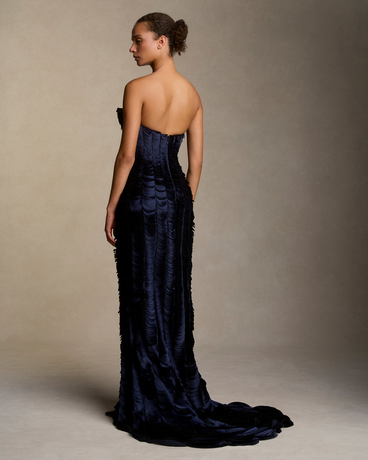 Strapless satin gown with flared neckline. Thousands of hand applied lasercut satin petals cascade down the body accentuating the silhouette. Boned internal bustier, internal grosgrain belt and invisible zip closure at center back.