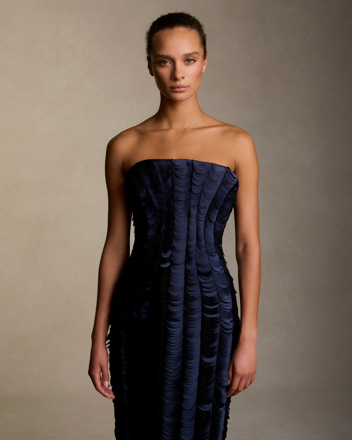 Strapless satin gown with flared neckline. Thousands of hand applied lasercut satin petals cascade down the body accentuating the silhouette. Boned internal bustier, internal grosgrain belt and invisible zip closure at center back.