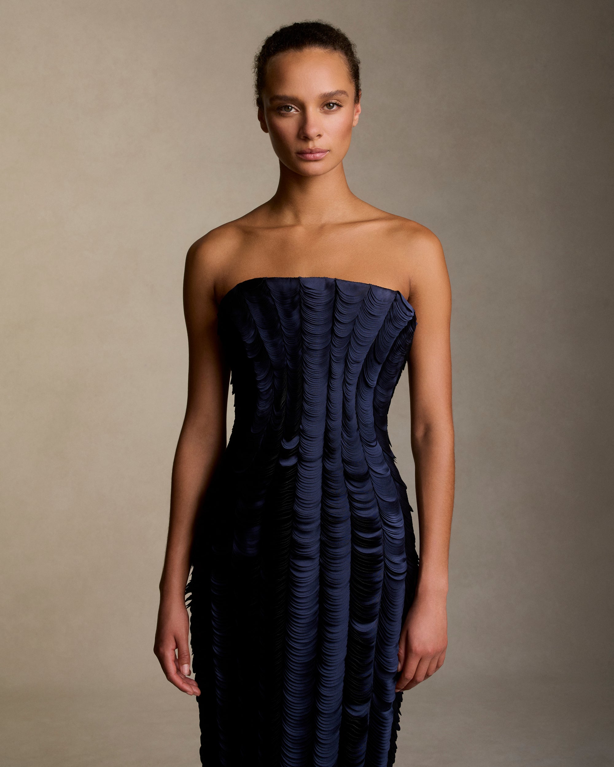 Strapless satin gown with flared neckline. Thousands of hand applied lasercut satin petals cascade down the body accentuating the silhouette. Boned internal bustier, internal grosgrain belt and invisible zip closure at center back.