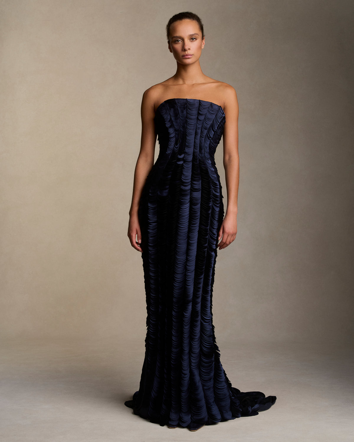 Strapless satin gown with flared neckline. Thousands of hand applied lasercut satin petals cascade down the body accentuating the silhouette. Boned internal bustier, internal grosgrain belt and invisible zip closure at center back.
