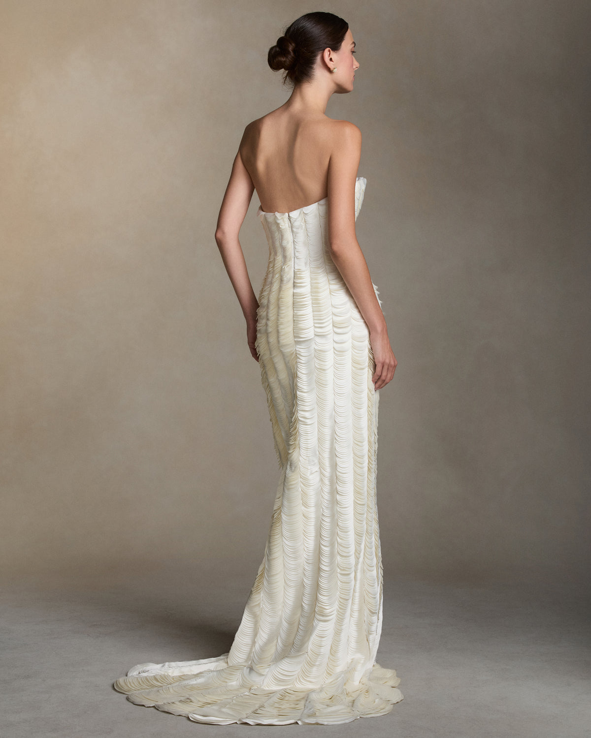 Strapless satin gown with flared neckline. Thousands of hand applied lasercut satin petals cascade down the body accentuating the silhouette. Boned internal bustier, internal grosgrain belt and invisible zip closure at center back.