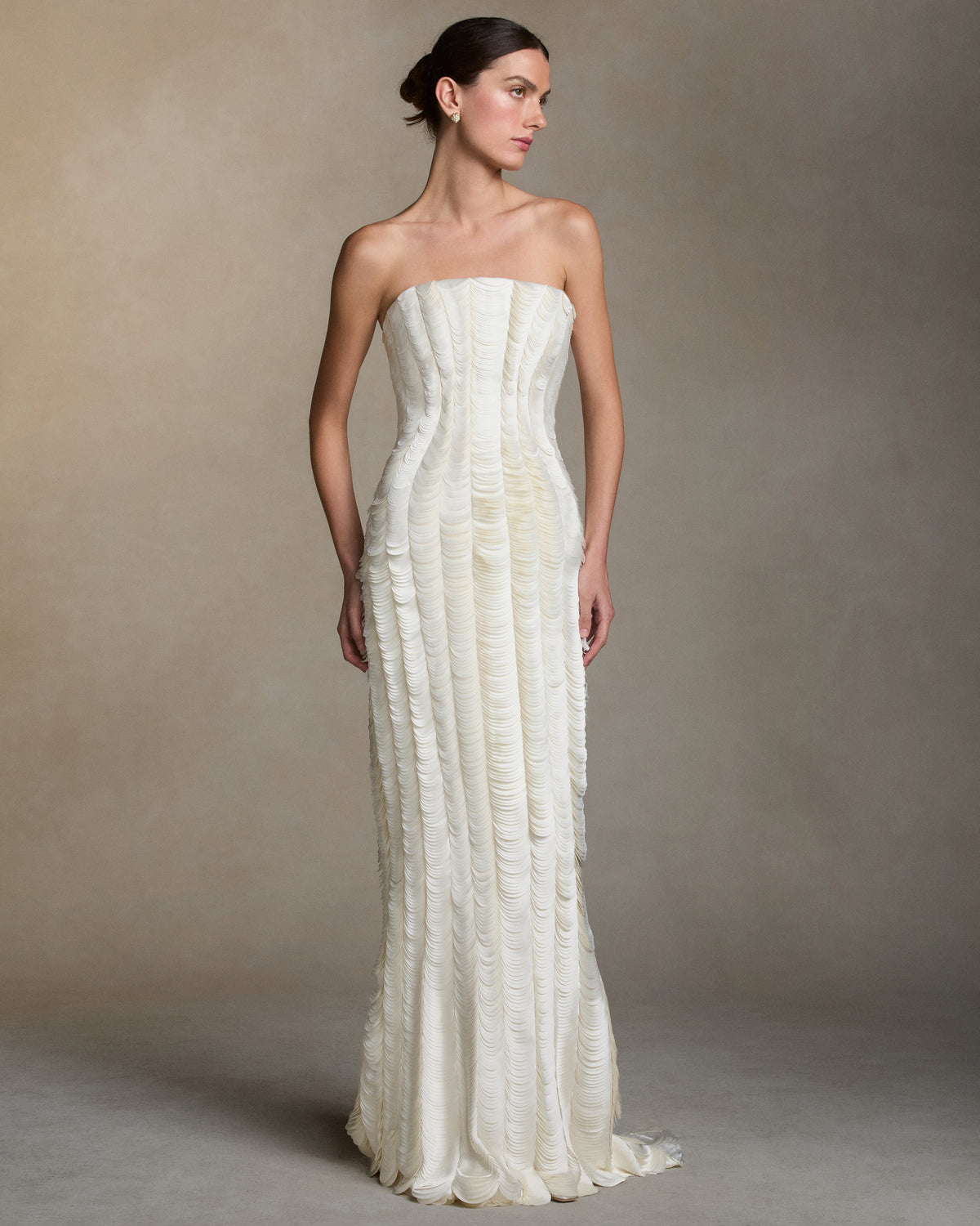 Strapless satin gown with flared neckline. Thousands of hand applied lasercut satin petals cascade down the body accentuating the silhouette. Boned internal bustier, internal grosgrain belt and invisible zip closure at center back.