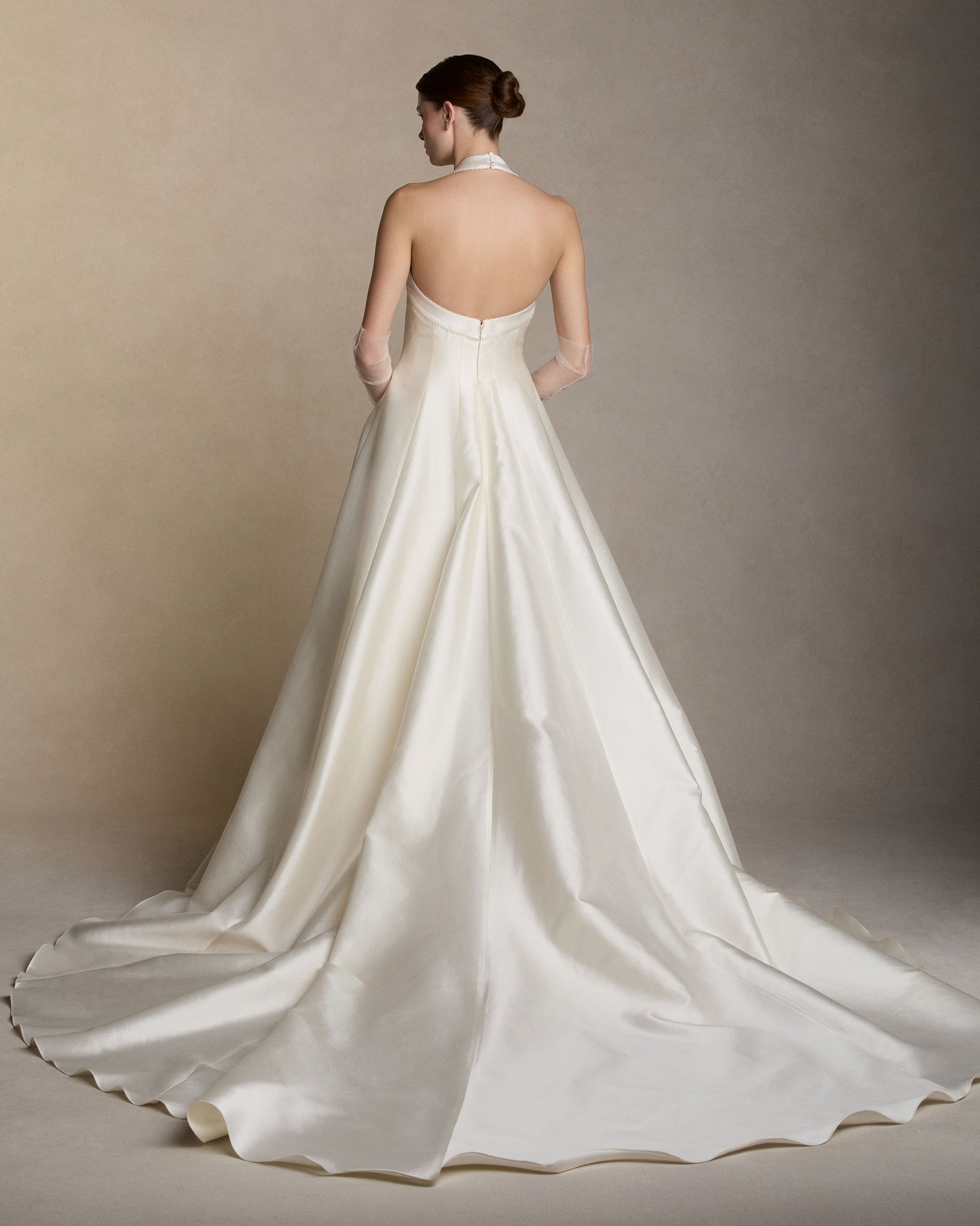 Silk wool twill halter-neck ball gown, finished with micro pearl-embroidered trim along the halter strap and neckline. Boned internal bustier, internal grosgrain belt and invisible zip closure at center back.Styled with Tulle Gloves
