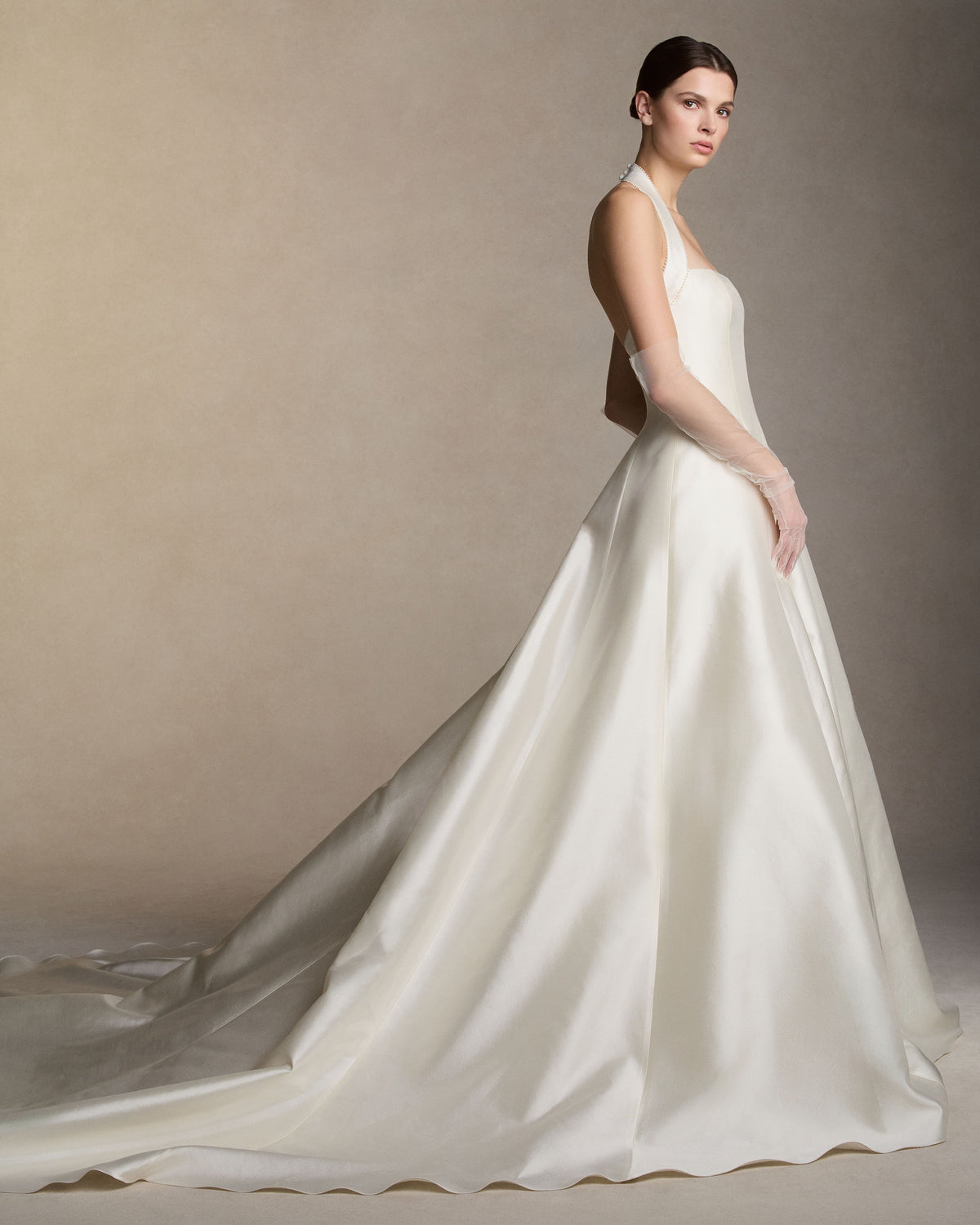 Silk wool twill halter-neck ball gown, finished with micro pearl-embroidered trim along the halter strap and neckline. Boned internal bustier, internal grosgrain belt and invisible zip closure at center back.Styled with Tulle Gloves
