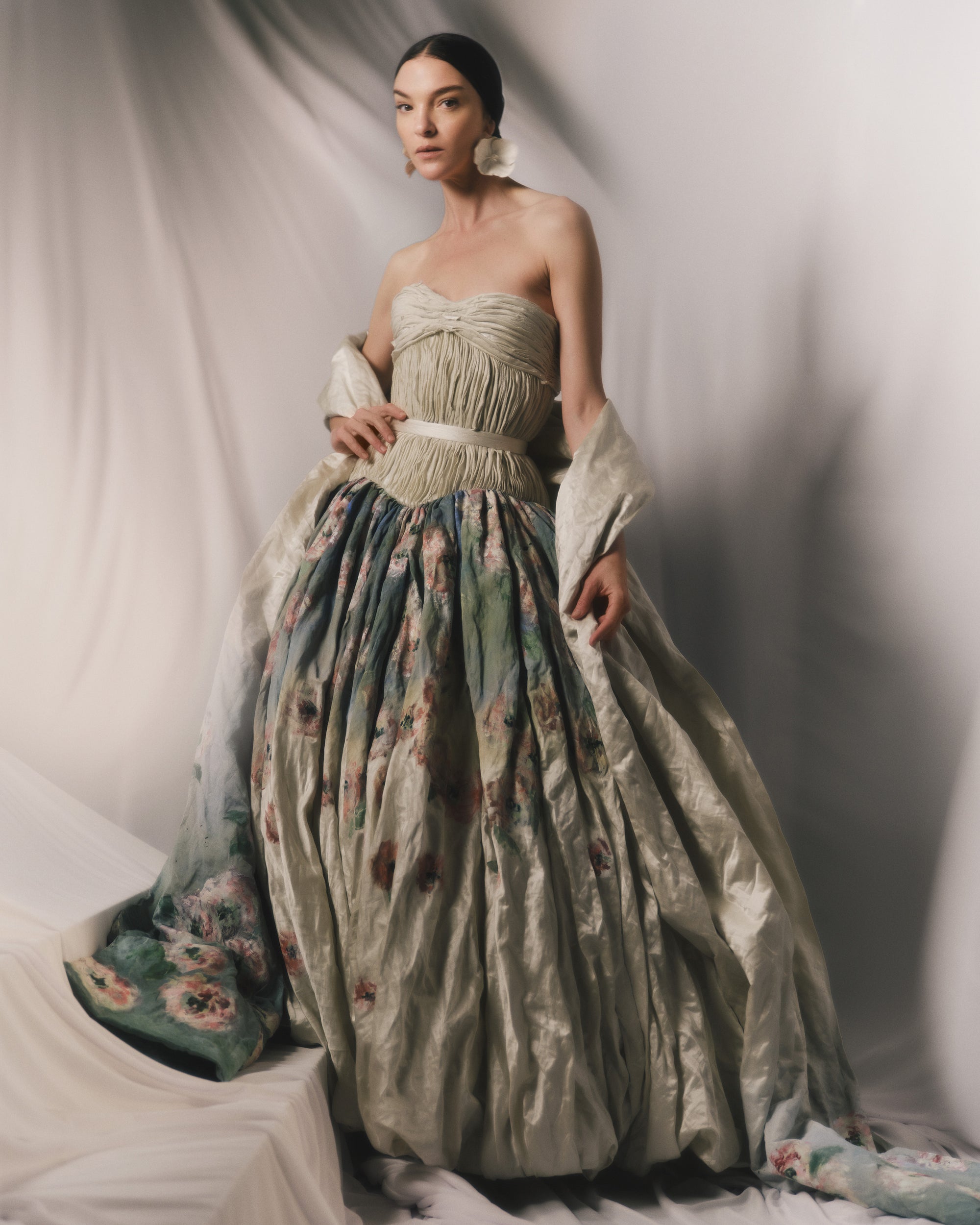 Strapless silk metal gown with hand painted florals that softly degrade down the lightly textured bubble hem skirt. Hand cut bias strip fabric technique decorates the bodice. Invisible zip closure at center back. Sold with self fabric belt. Available without hand painting as well, inquire atelier@daniellefrankelstudio.com for pricing