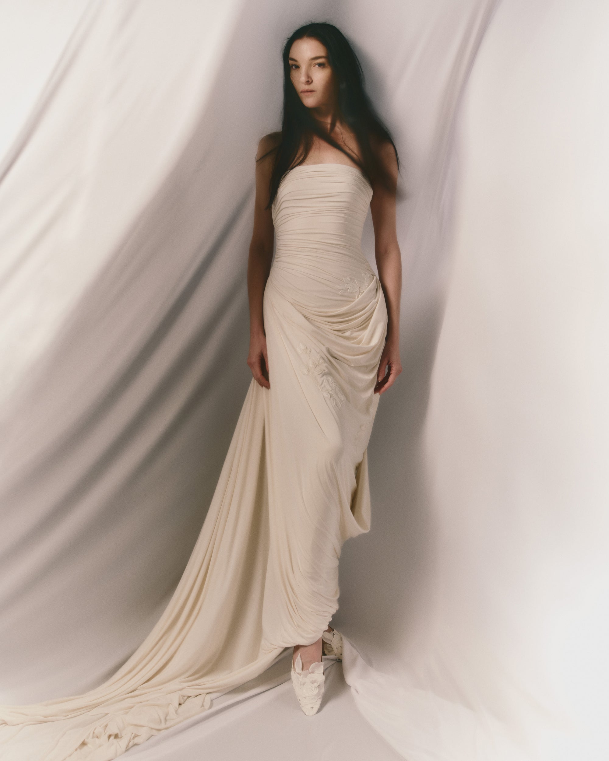 Fluid jersey strapless gown with asymmetric cascading drape and hand painted floral motifs throughout. Puddle train detail. Invisible zip closure at center back.
