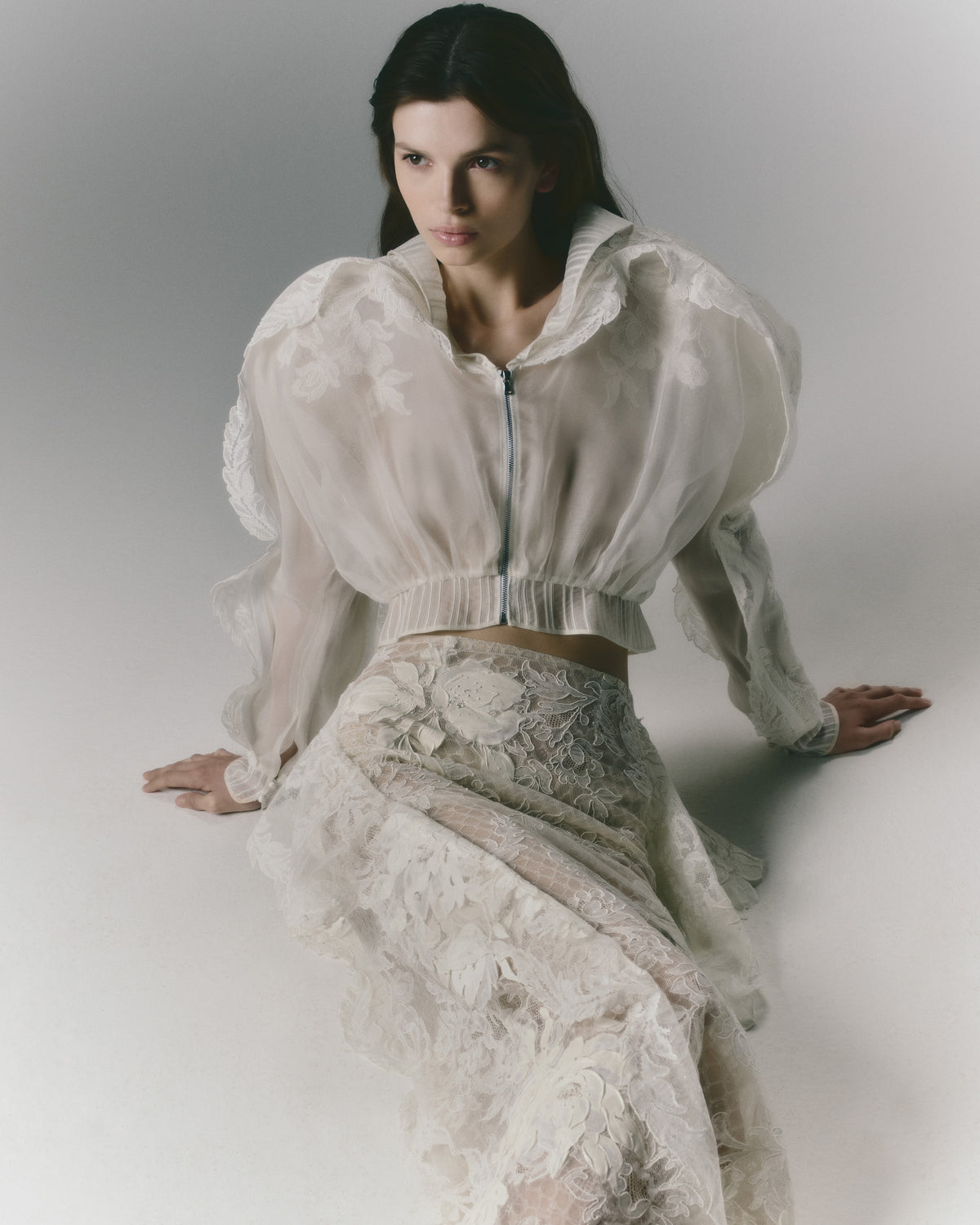 Silk organza jacket adorned with Lyon lace appliques. Lyon lace trim peeks out of a piped organza trimmed yoke. Separating zip closure at center front.Styled with Laila skirt