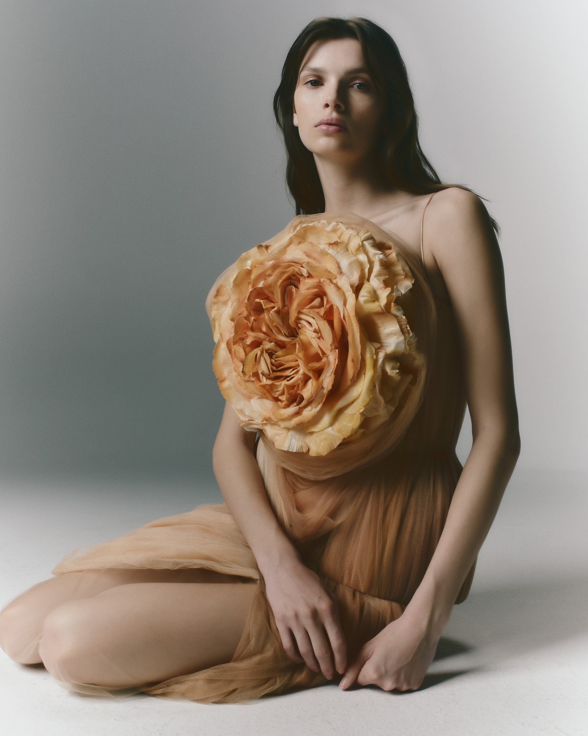 Hand dyed ombre soft tulle bustier with nipped waist and structured hip shape. A hand crafted clay rose blooms from layers of soft tulle at bust. Separating zipper closure at center back.