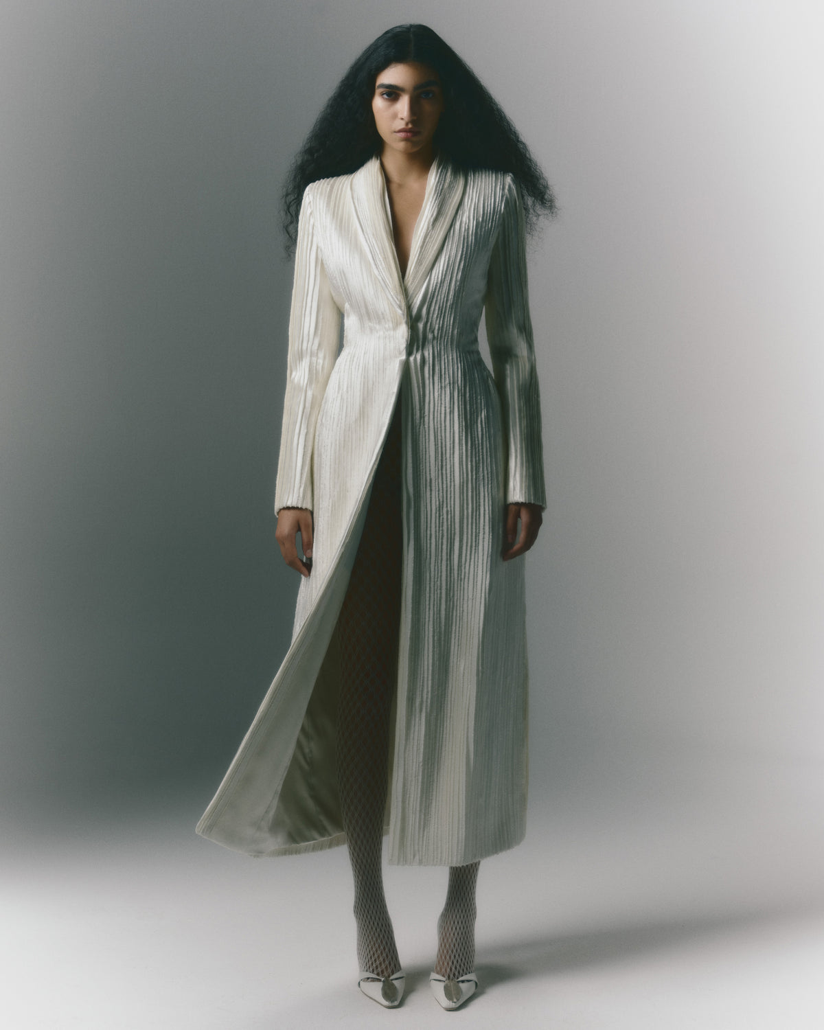 Tailored coat decorated with hand cut and hand frayed bias silk wool strip fabric technique embroidery. Nipped waist and structured hip shape. Side seam pockets and single snap closure at center front.
