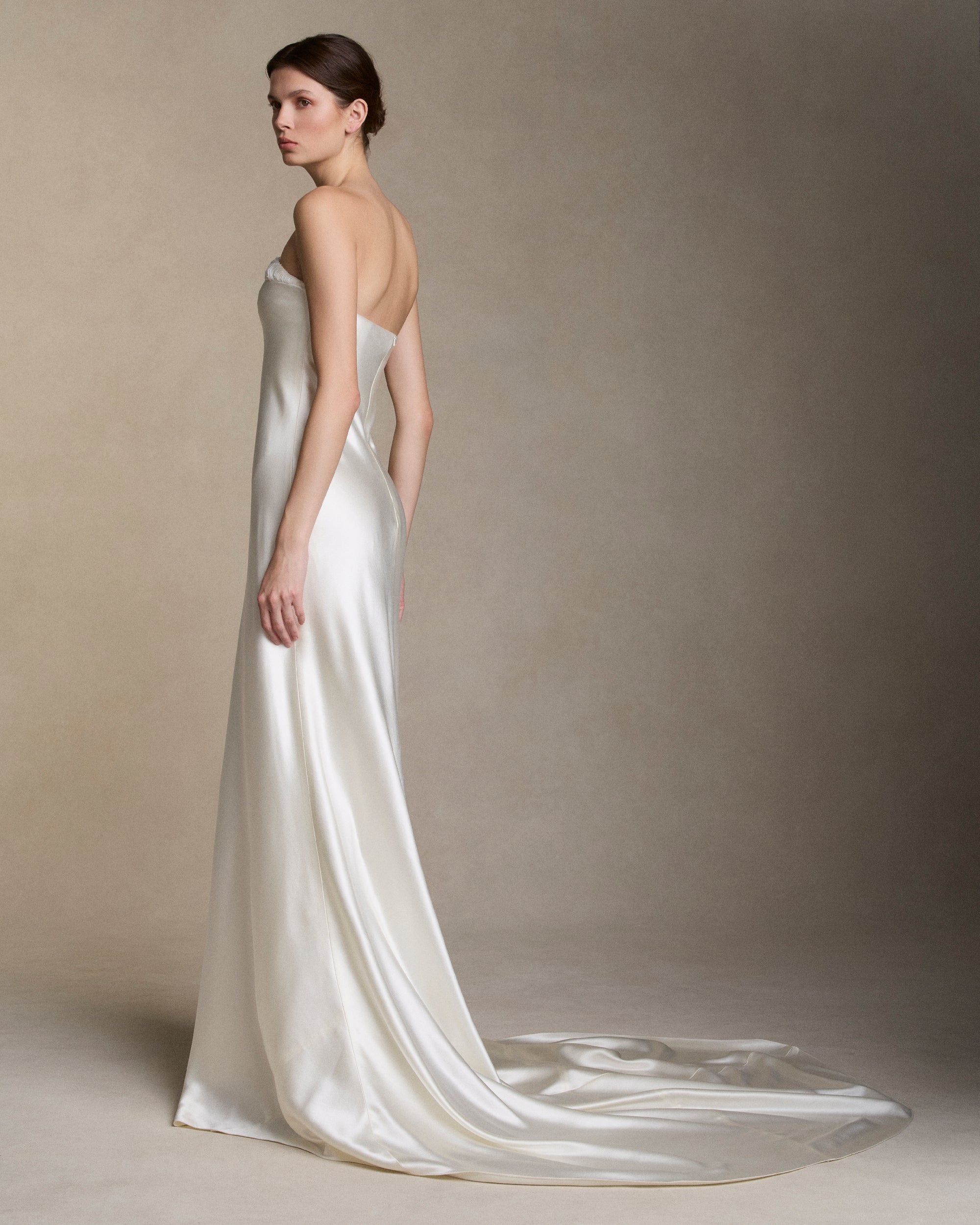 Strapless silk wool bias cut gown with hand cut silk wool petal embroidery decorating the neckline. Boned internal bustier with soft cups, internal grosgrain belt and invisible zip closure at center back.