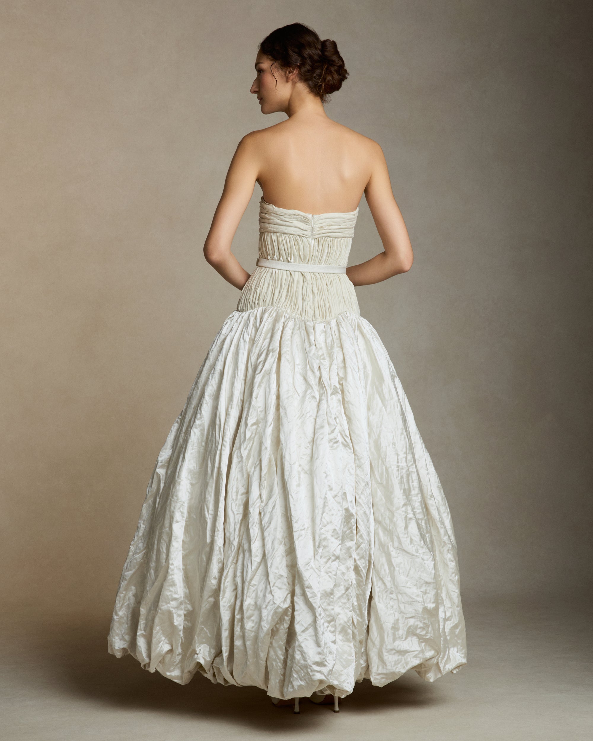 Strapless silk metal gown with hand painted florals that softly degrade down the lightly textured bubble hem skirt. Hand cut bias strip fabric technique decorates the bodice. Invisible zip closure at center back. Sold with self fabric belt. Available without hand painting as well, inquire atelier@daniellefrankelstudio.com for pricing