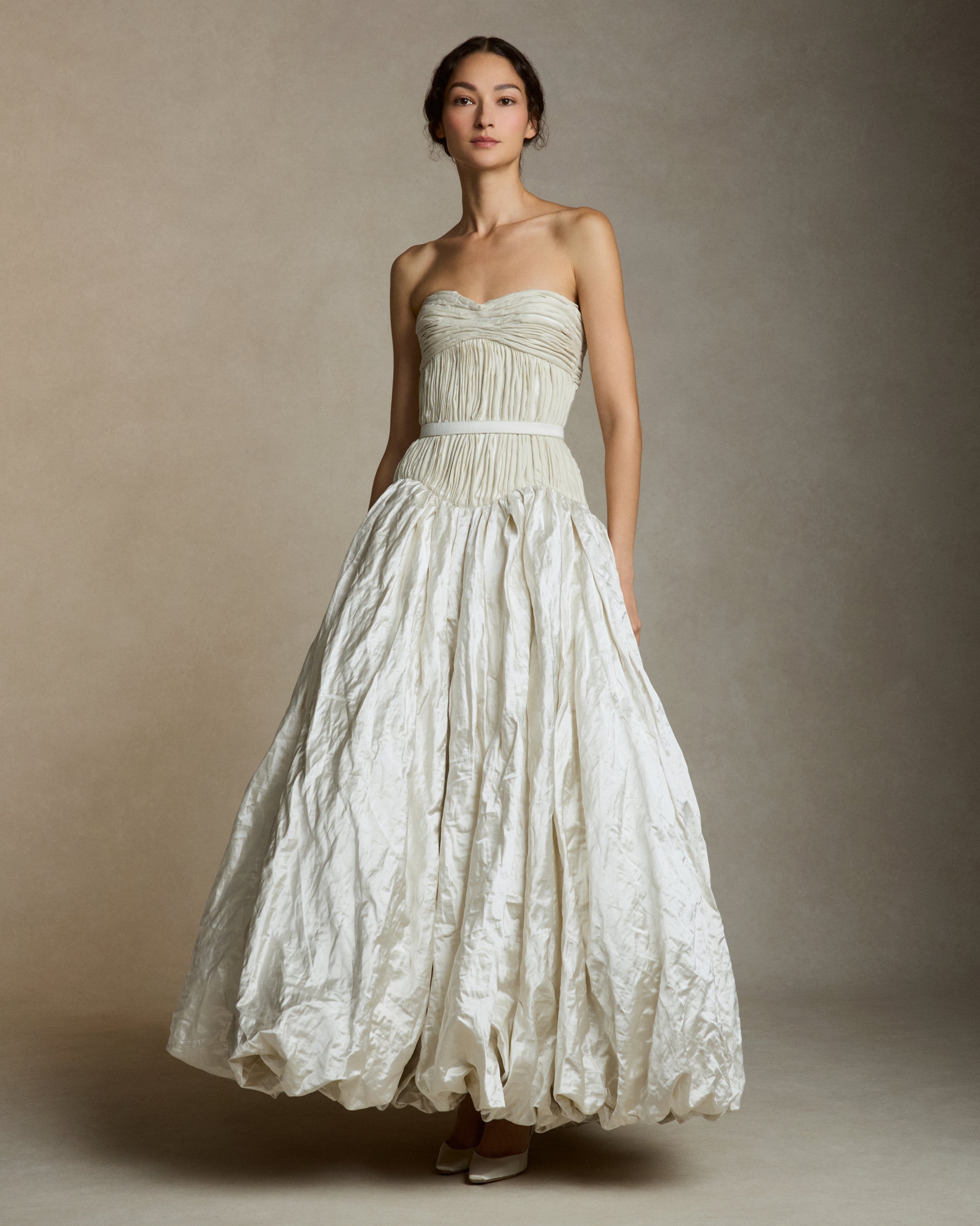 Strapless silk metal gown with hand painted florals that softly degrade down the lightly textured bubble hem skirt. Hand cut bias strip fabric technique decorates the bodice. Invisible zip closure at center back. Sold with self fabric belt. Available without hand painting as well, inquire atelier@daniellefrankelstudio.com for pricing