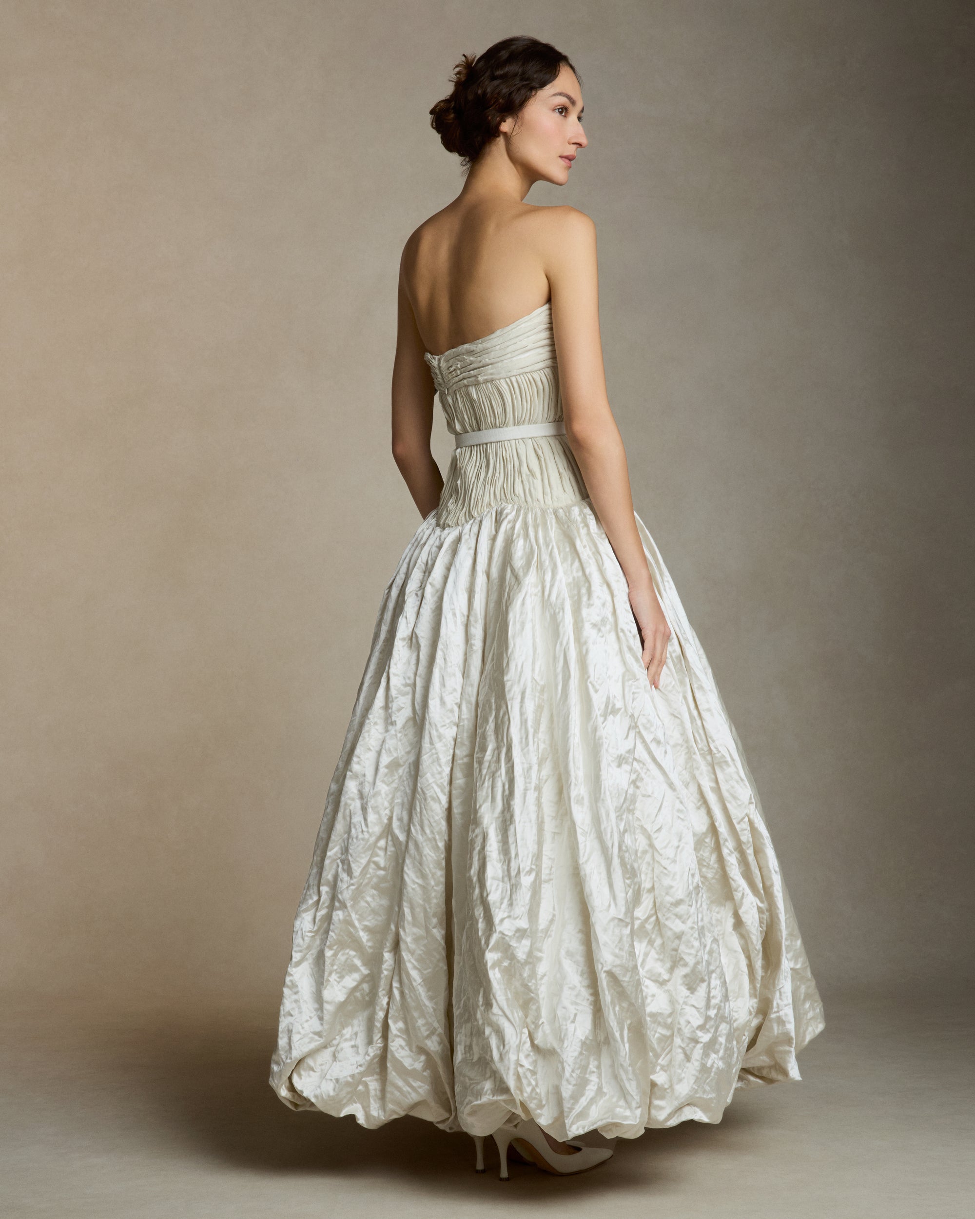 Strapless silk metal gown with hand painted florals that softly degrade down the lightly textured bubble hem skirt. Hand cut bias strip fabric technique decorates the bodice. Invisible zip closure at center back. Sold with self fabric belt. Available without hand painting as well, inquire atelier@daniellefrankelstudio.com for pricing