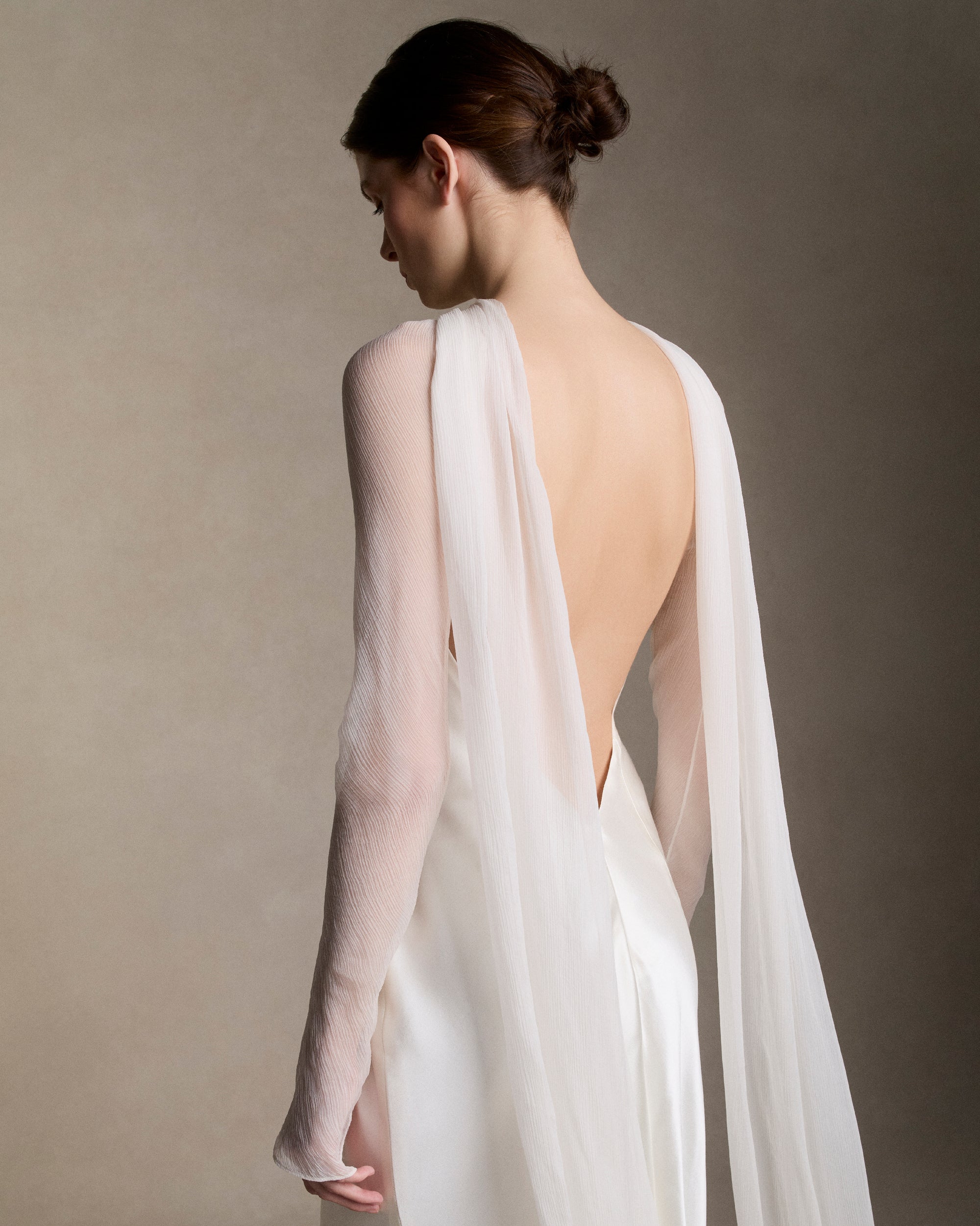 Removable tulle sleeves drape across center front falling into a scarf train detail at center back.  