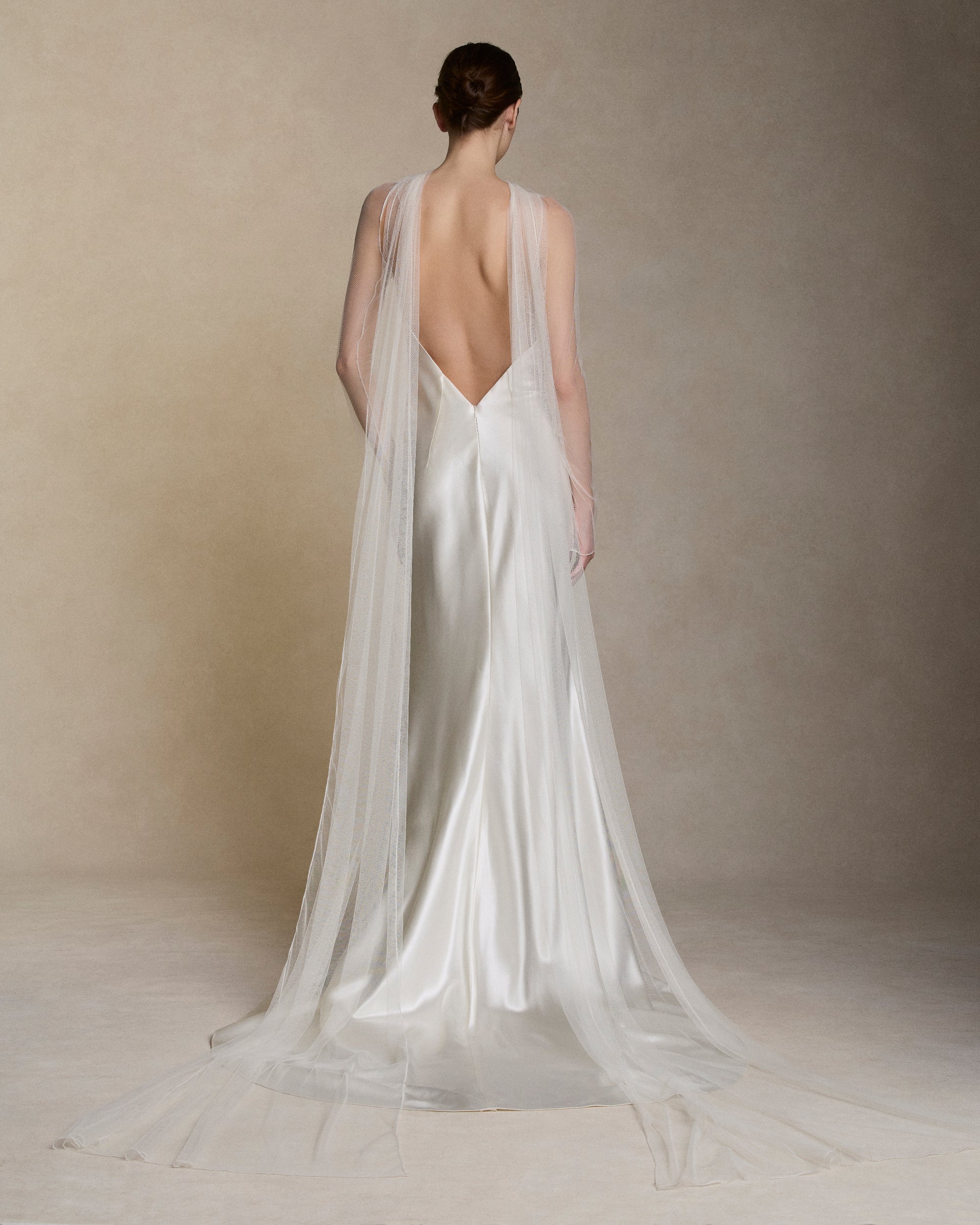 Removable tulle sleeves drape across center front falling into a scarf train detail at center back.  