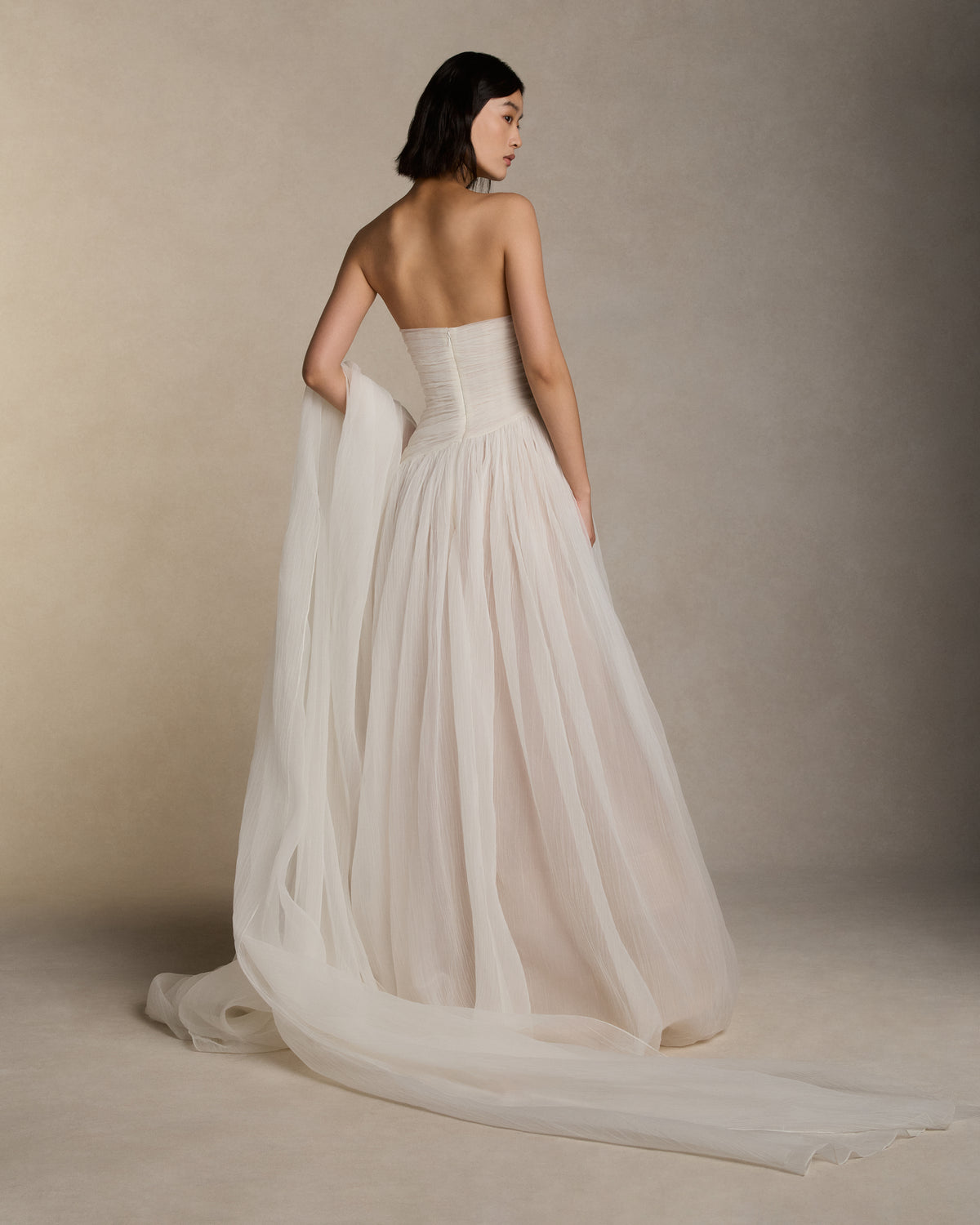 Crinkle organza strapless ball gown draped bodice and asymmetric diagonal waistline. Relaxed crinkle organza skirt ball skirt with straight hem. Boned internal bustier, internal grosgrain belt and invisible zip closure at center back.