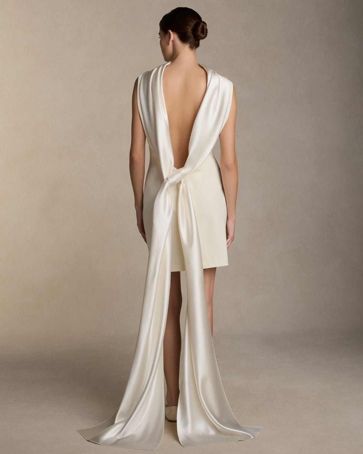 Matte wool viscose high neck bias cut dress. Luminous silk wool drapes across the décolletage and falls into an open back, descending into a scarf drape train. Invisible zip closure at center back.