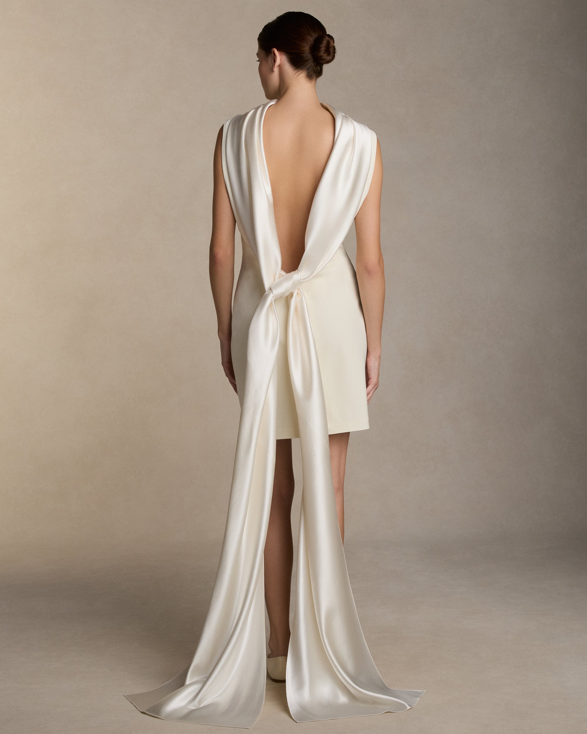 Matte wool viscose high neck bias cut dress. Luminous silk wool drapes across the décolletage and falls into an open back, descending into a scarf drape train. Invisible zip closure at center back.
