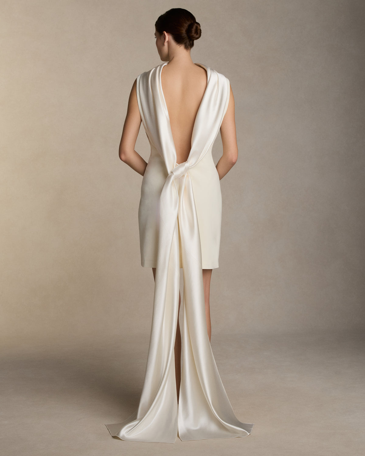 Matte wool viscose high neck bias cut dress. Luminous silk wool drapes across the décolletage and falls into an open back, descending into a scarf drape train. Invisible zip closure at center back.