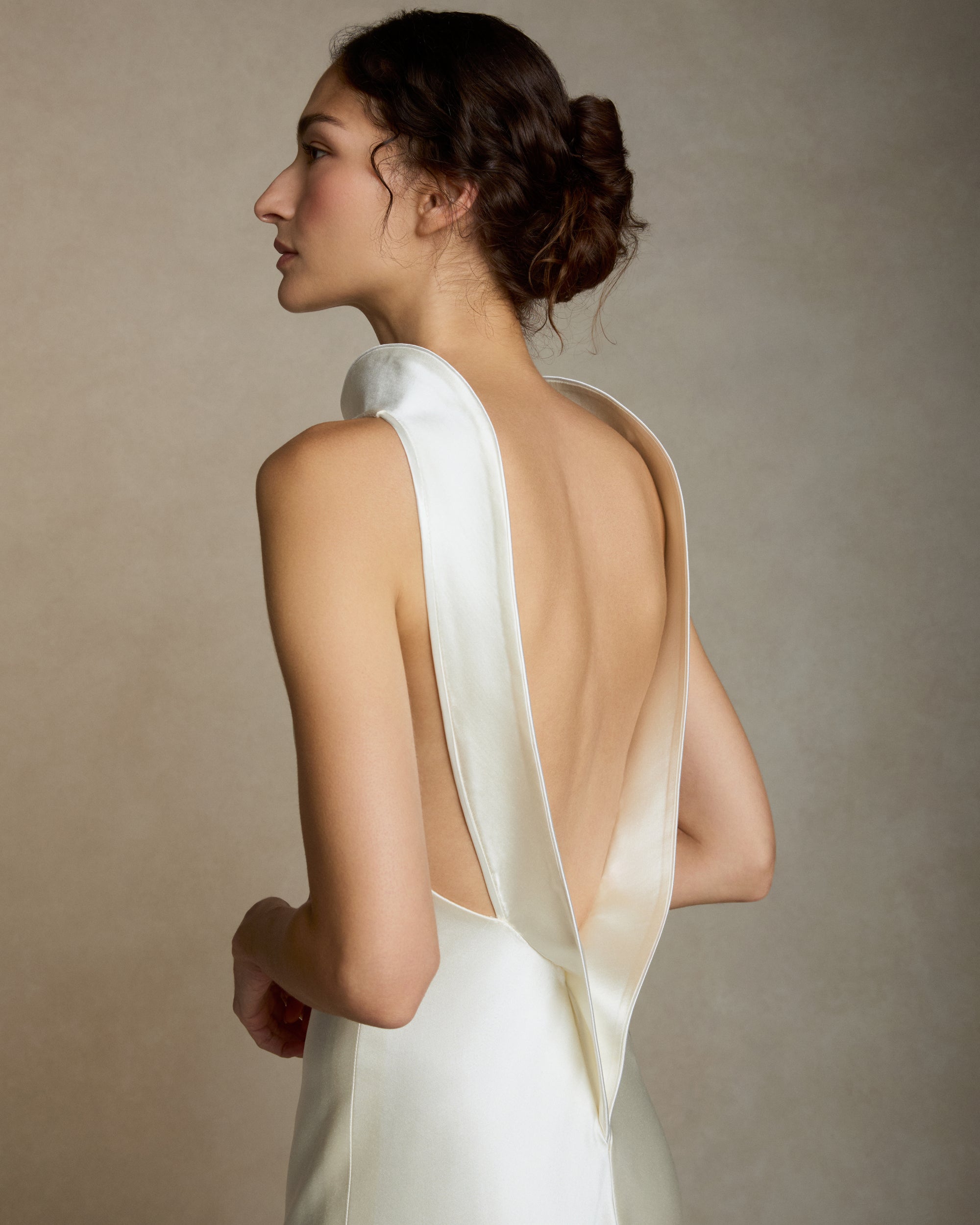 Silk wool high neck bias cut gown. Piped silk wool trim frames the neckline falling into a sculpted deep V at center back. Adjustable neck trim can be worn as a mock neck or peeled away from neckline. Invisible zip closure at center back.