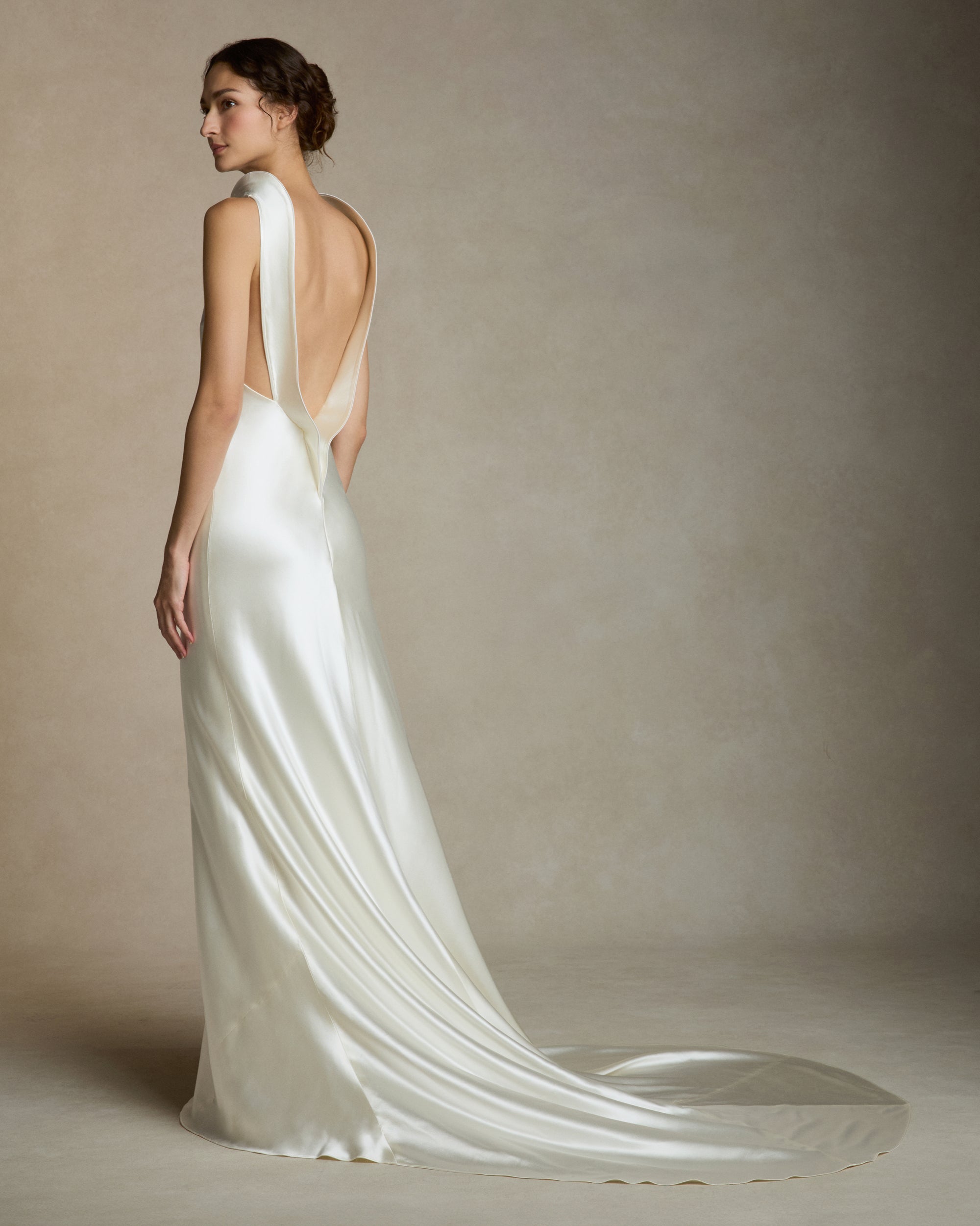 Silk wool high neck bias cut gown. Piped silk wool trim frames the neckline falling into a sculpted deep V at center back. Adjustable neck trim can be worn as a mock neck or peeled away from neckline. Invisible zip closure at center back.