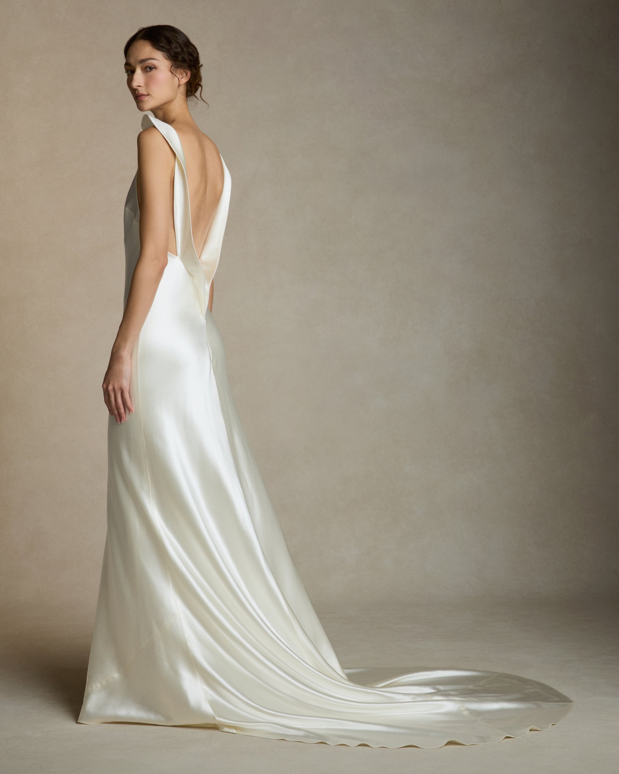 Silk wool high neck bias cut gown. Piped silk wool trim frames the neckline falling into a sculpted deep V at center back. Adjustable neck trim can be worn as a mock neck or peeled away from neckline. Invisible zip closure at center back.