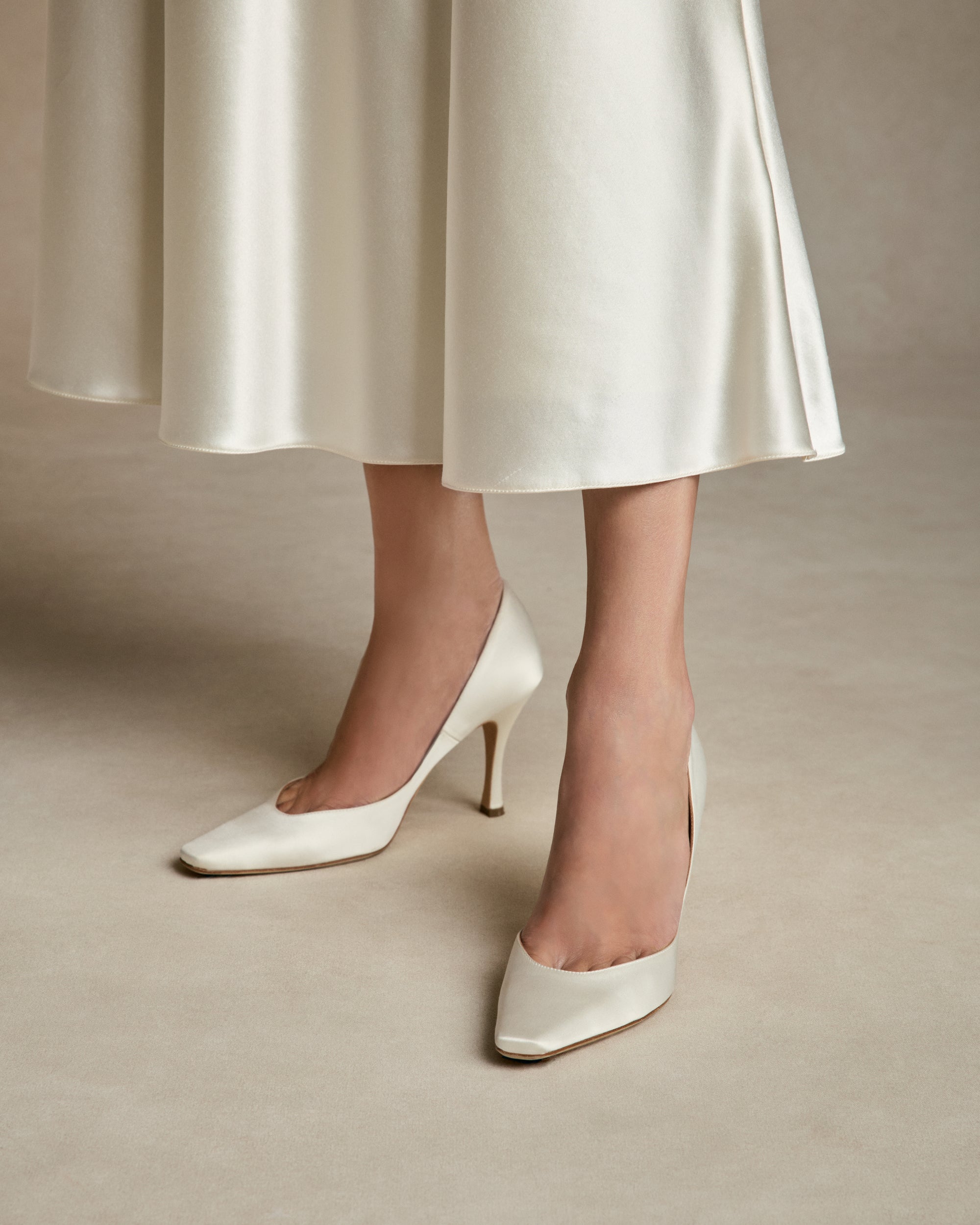  Sleek rounded square toe classic pump crafted in Italy of ivory satin. 90mm heel. 