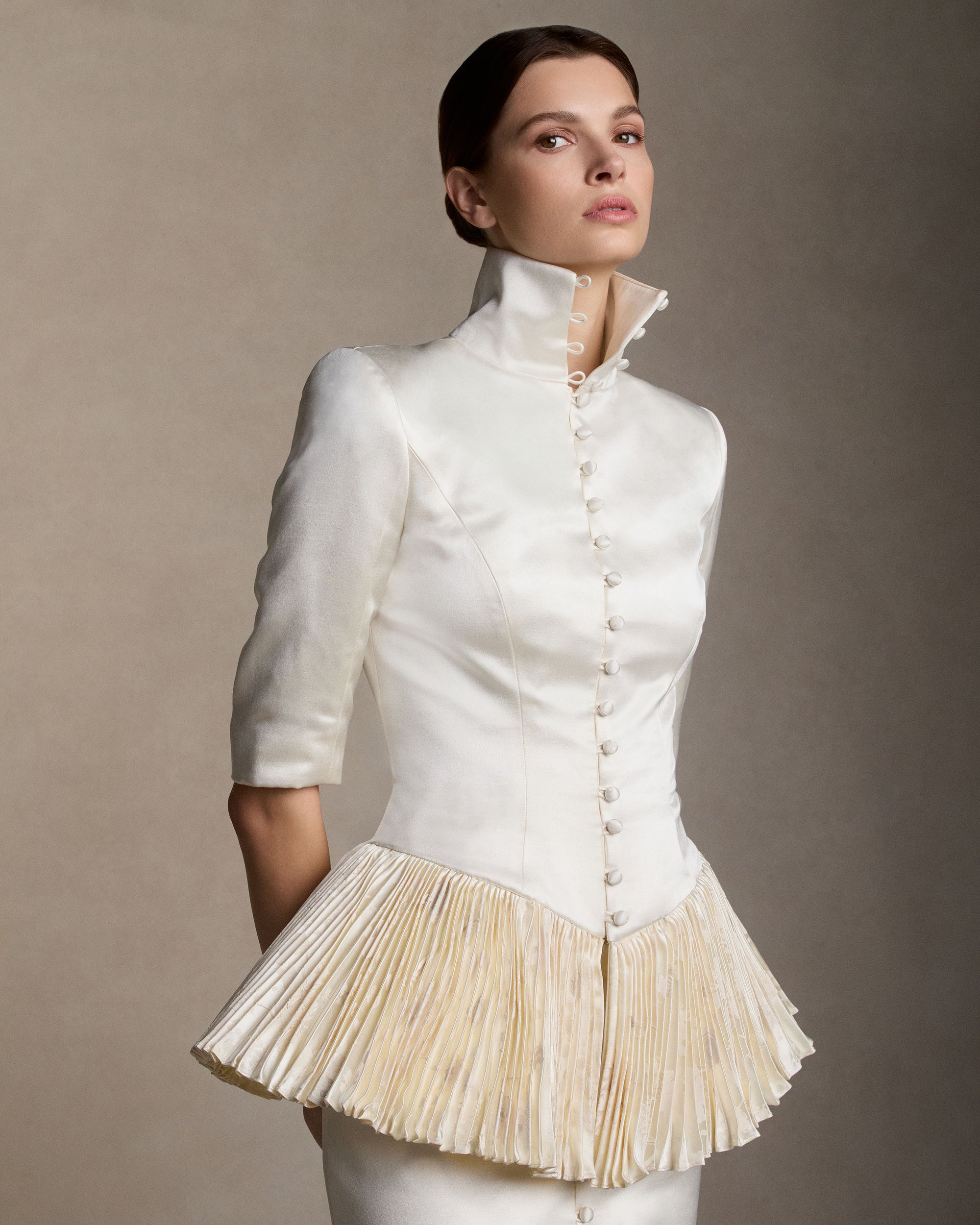 Tailored jacket in silk wool satin with shaped seams finished with a sharp pleated peplum in pigment-printed, hand-painted silk wool. Center front covered button closure.Styled with Ulli skirt